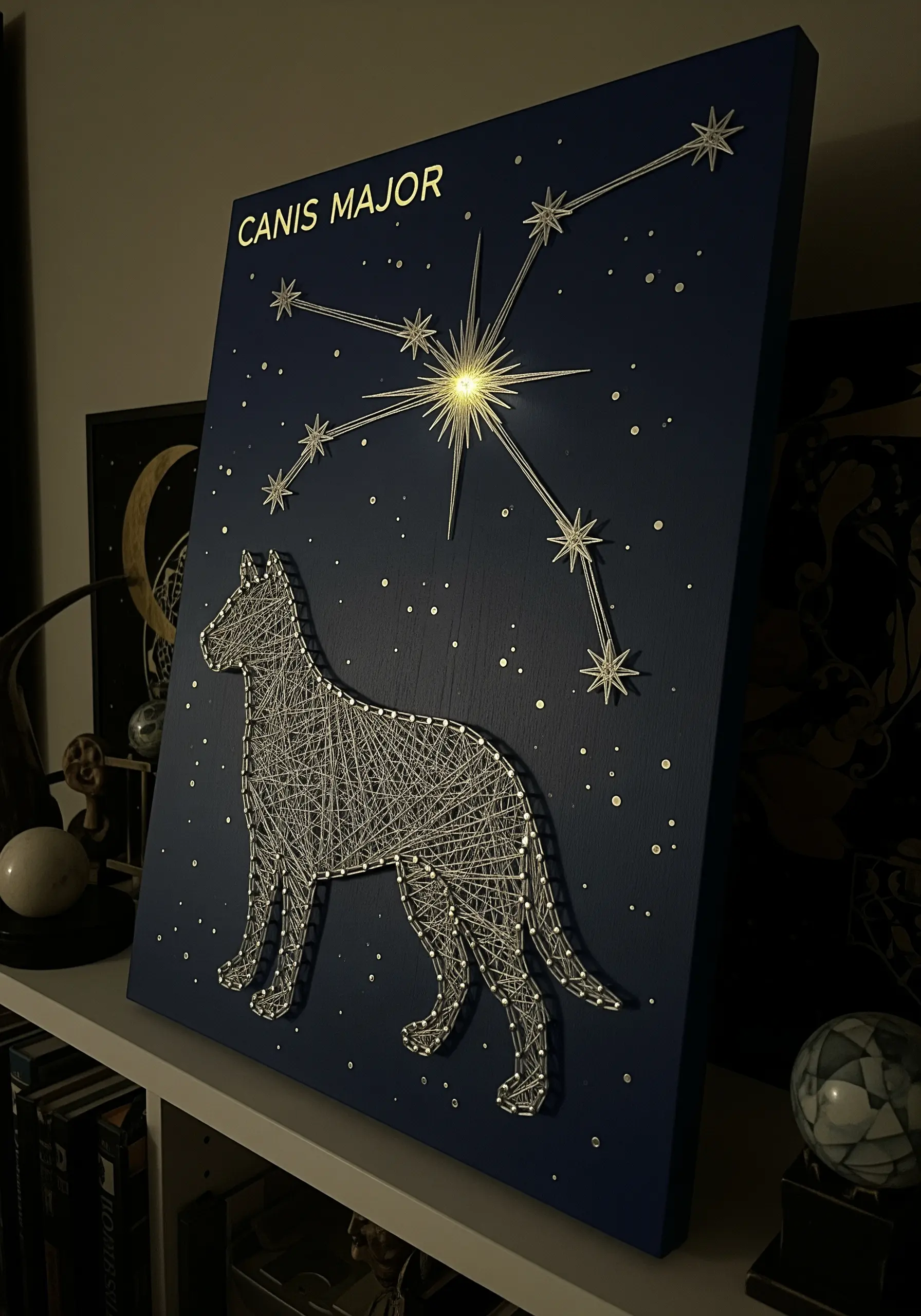 String art of a dog silhouette connected to a Canis Major constellation on a blue board.
