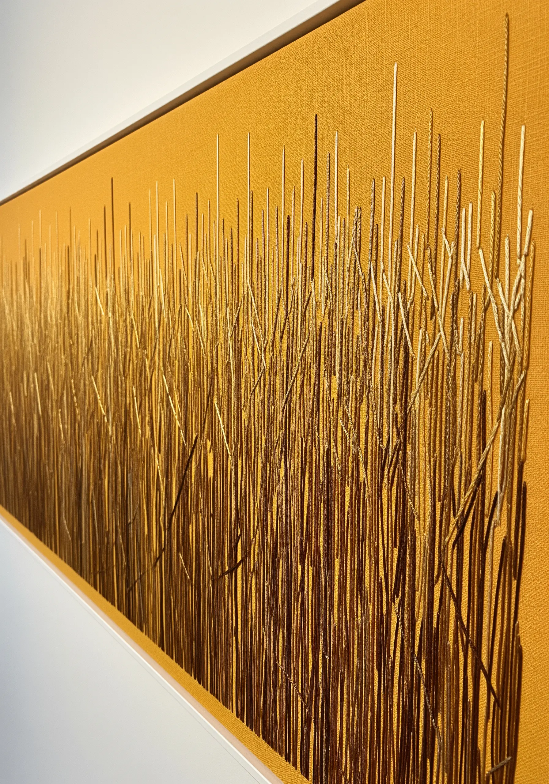 An abstract field of wheat made with vertical gold stitches of varying heights and textures.