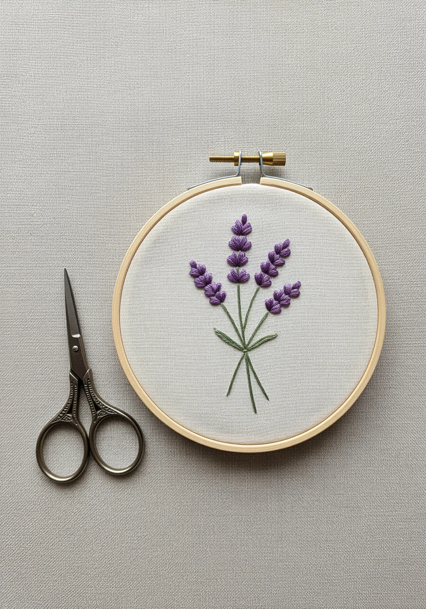 Hand-embroidered lavender sprigs in a wooden hoop with scissors nearby.