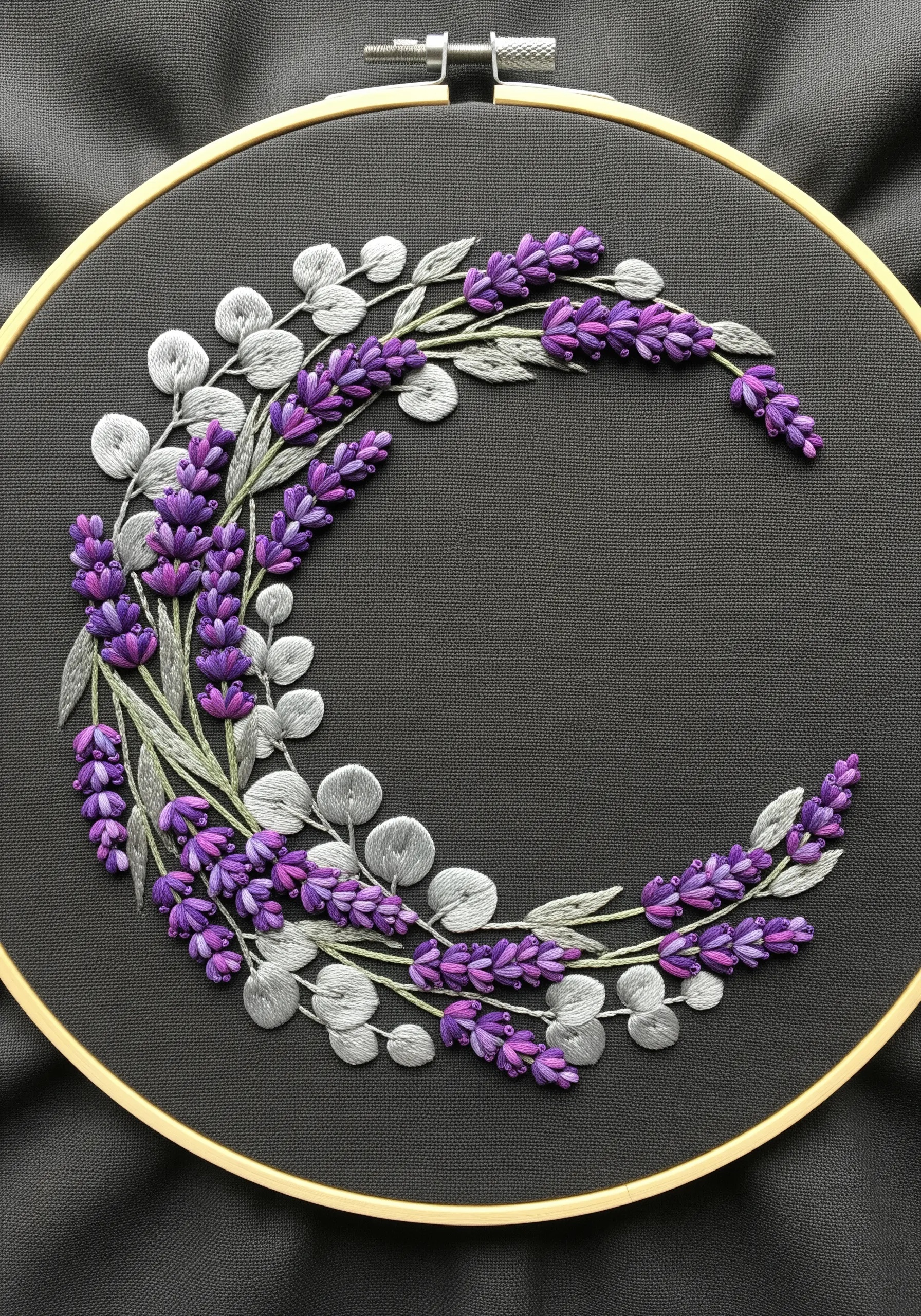 A crescent moon shape made of lavender and silver leaves on dark gray fabric.