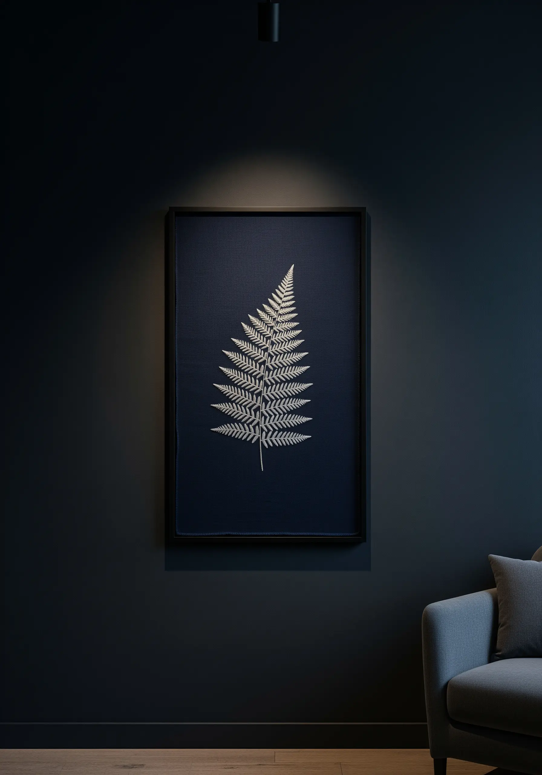A single, detailed fern leaf embroidered in white thread on dark navy fabric.