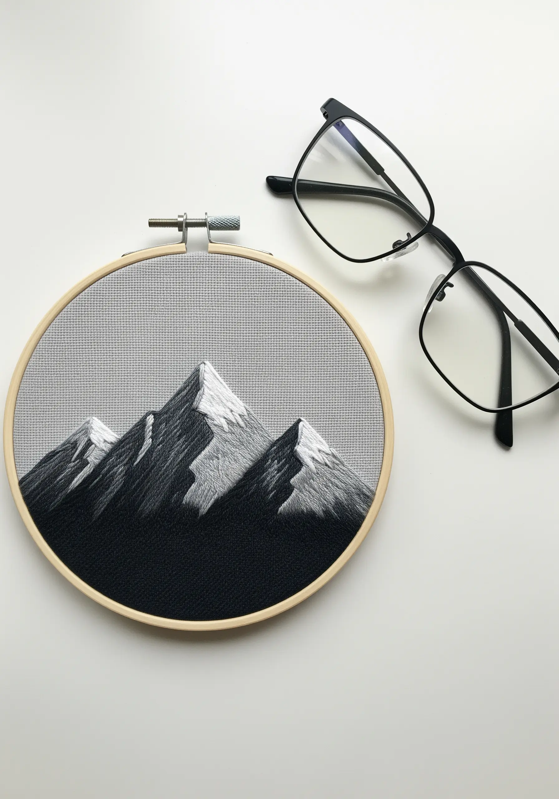 A monochrome mountain landscape with thread-painted shadows and highlights.