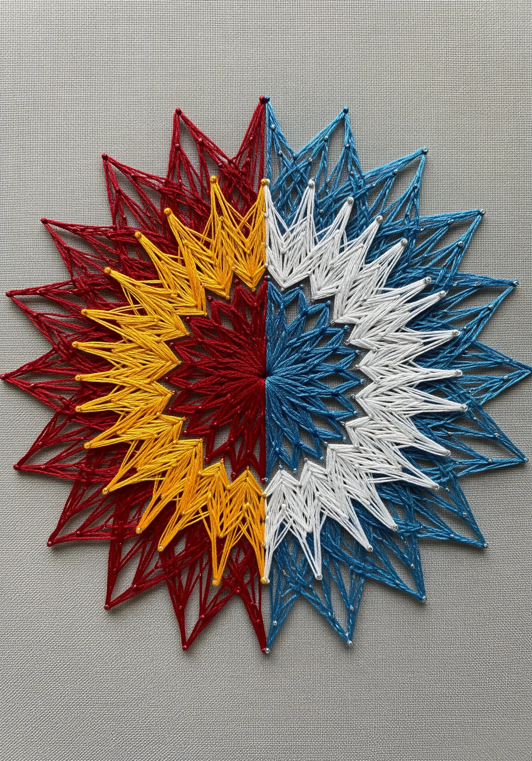 String art star divided into four color sections: red/yellow and blue/white.