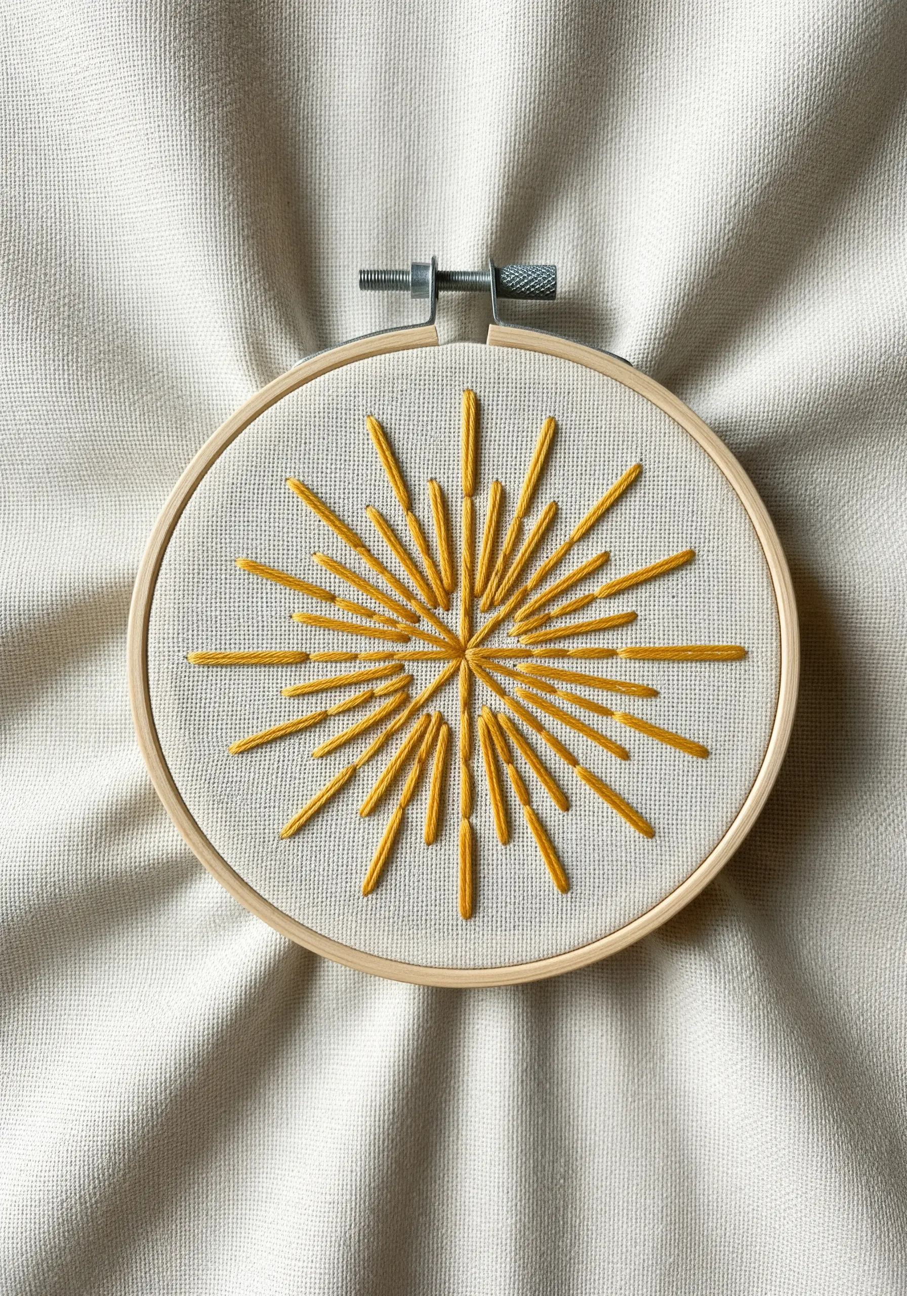 Embroidered yellow starburst made with straight stitches of varying lengths.