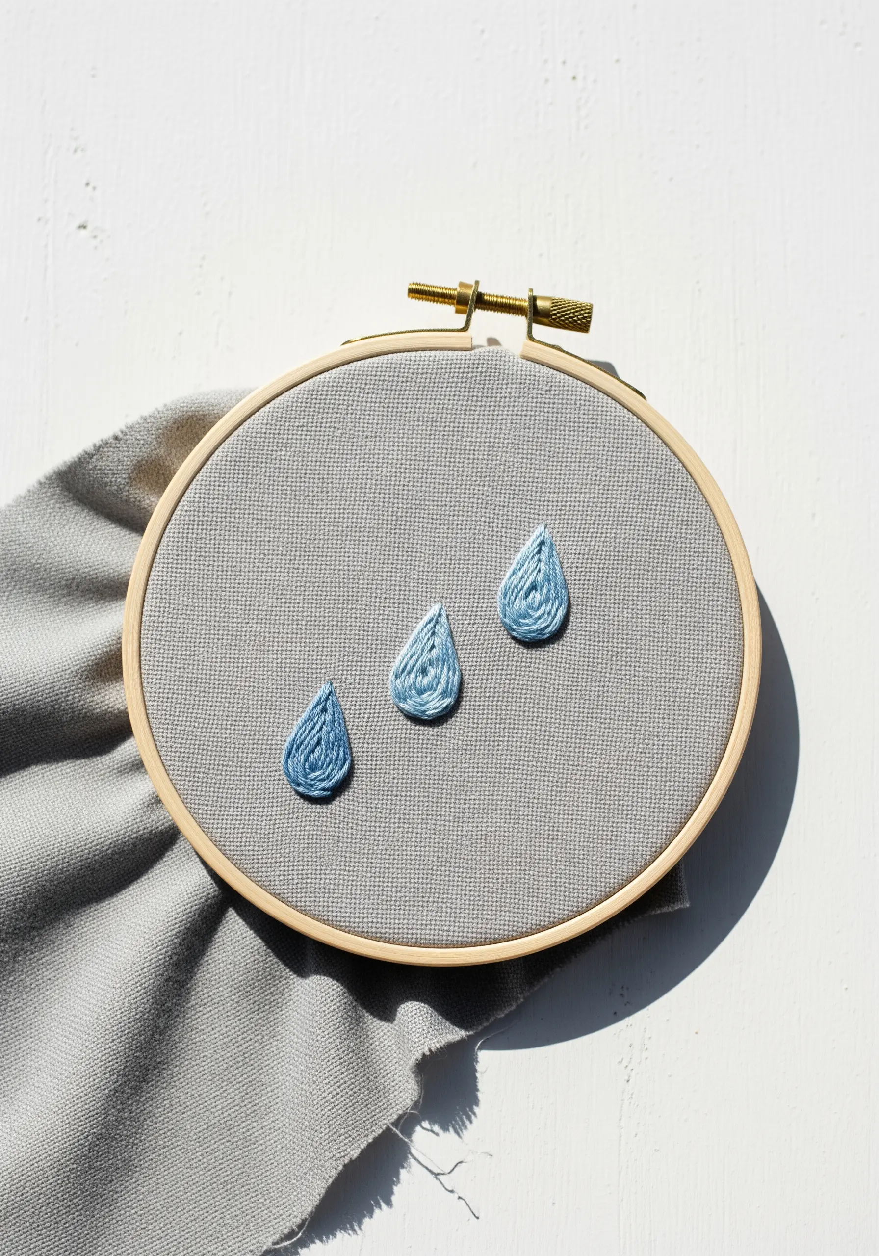 Three embroidered raindrops, each filled with a smooth gradient of blue satin stitches.