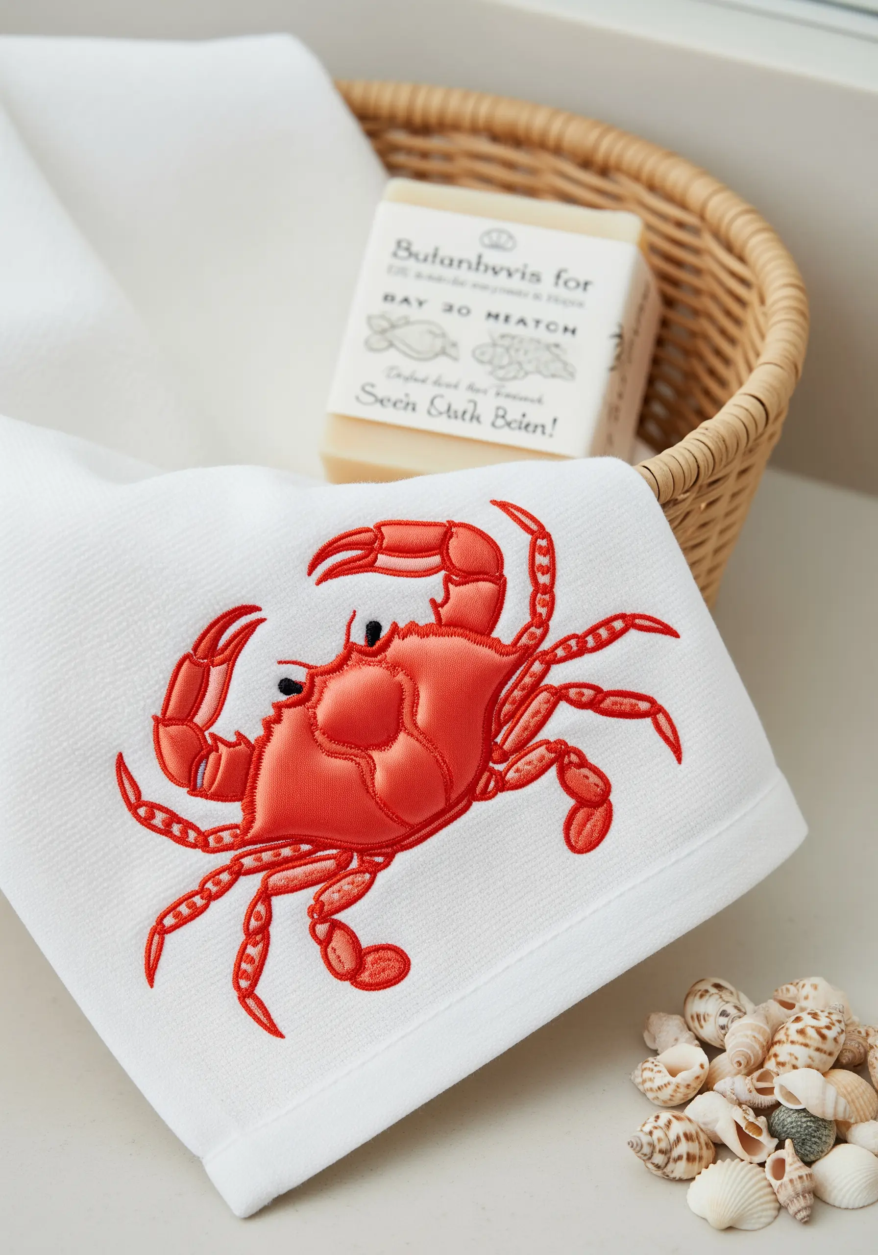A bright red crab embroidered on a white towel with clean satin stitch.