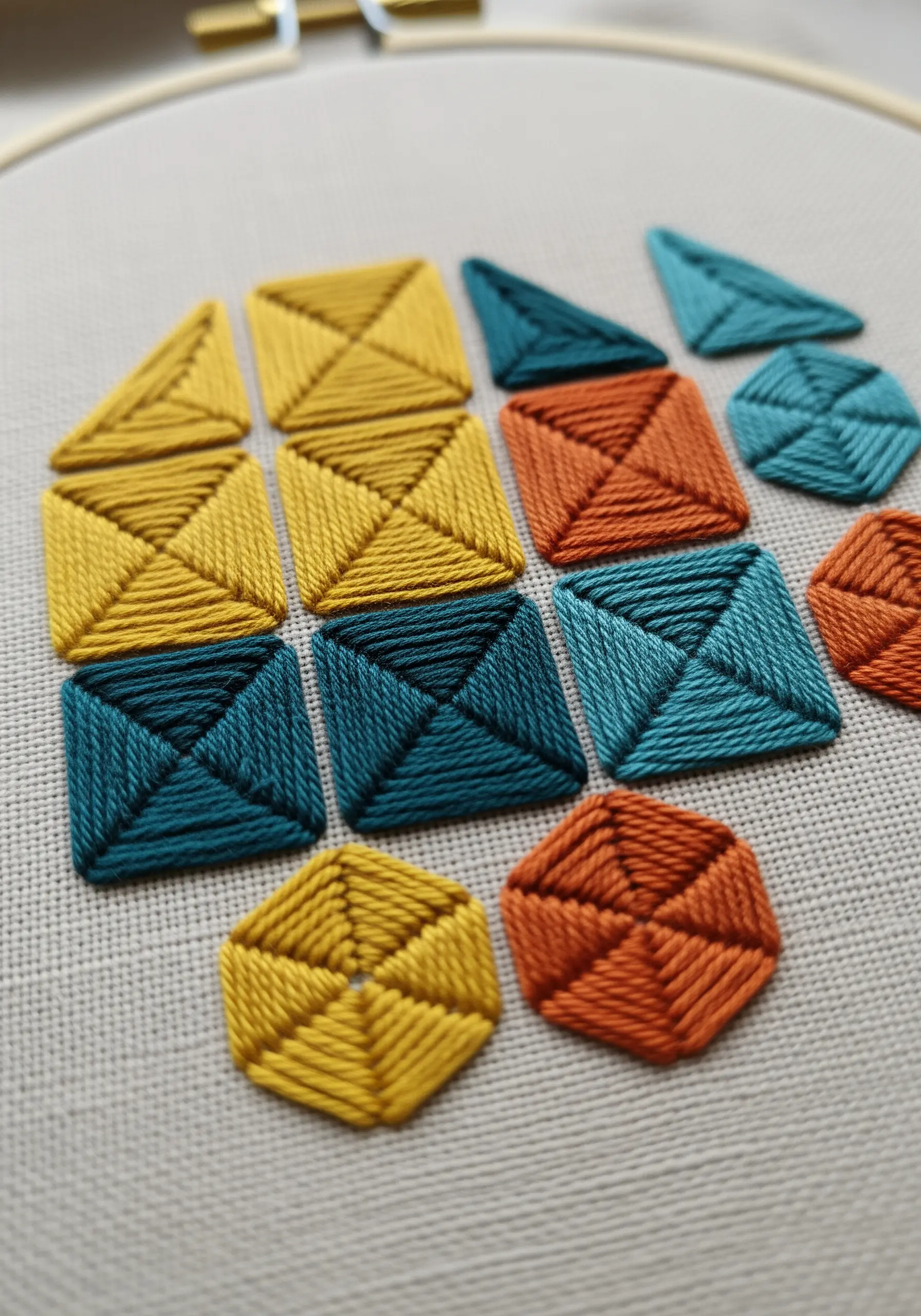 A collection of geometric shapes filled with colored thread in a grid-like pattern.