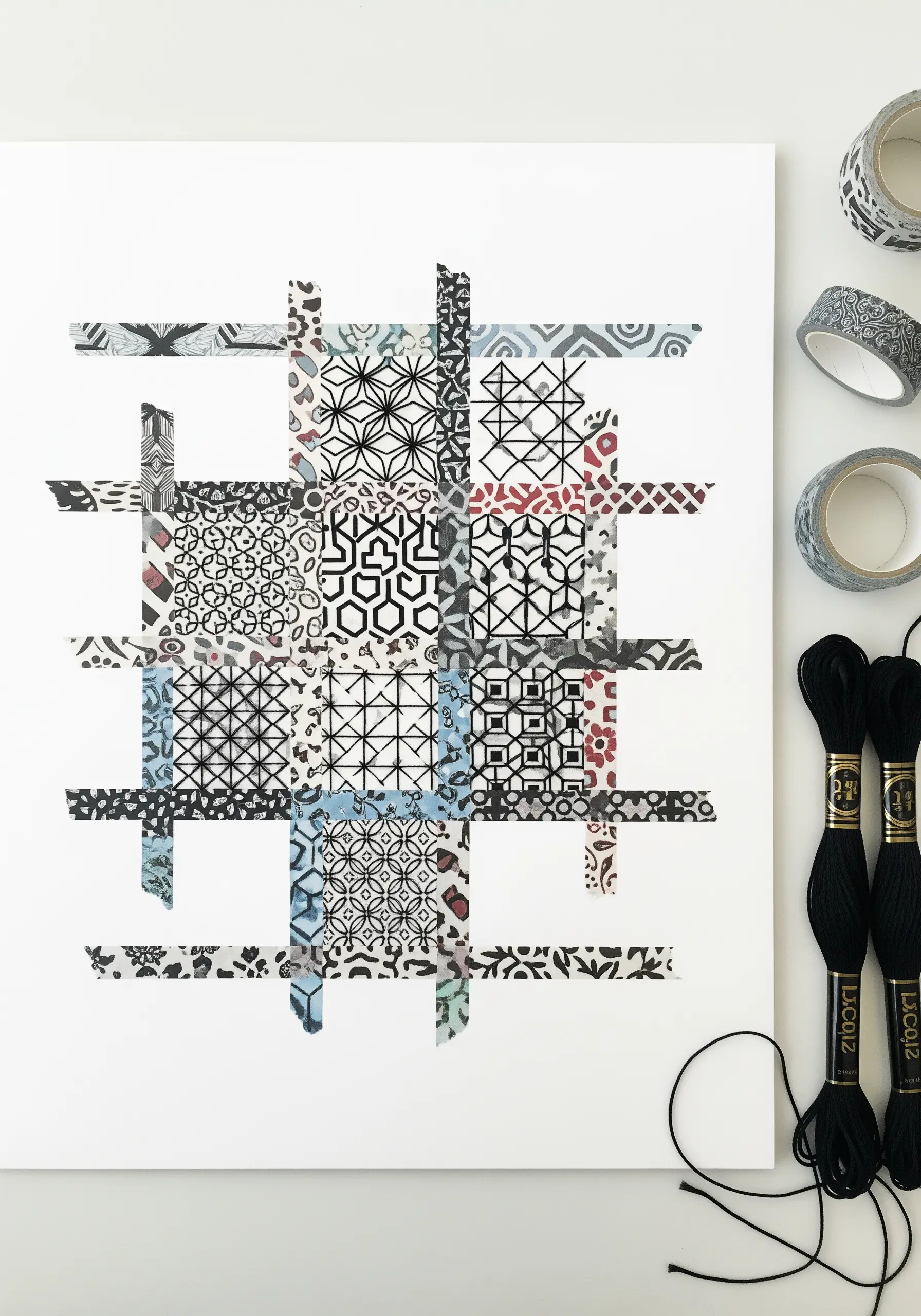 A geometric collage made from patterned washi tape on paper, with black thread stitched over it.
