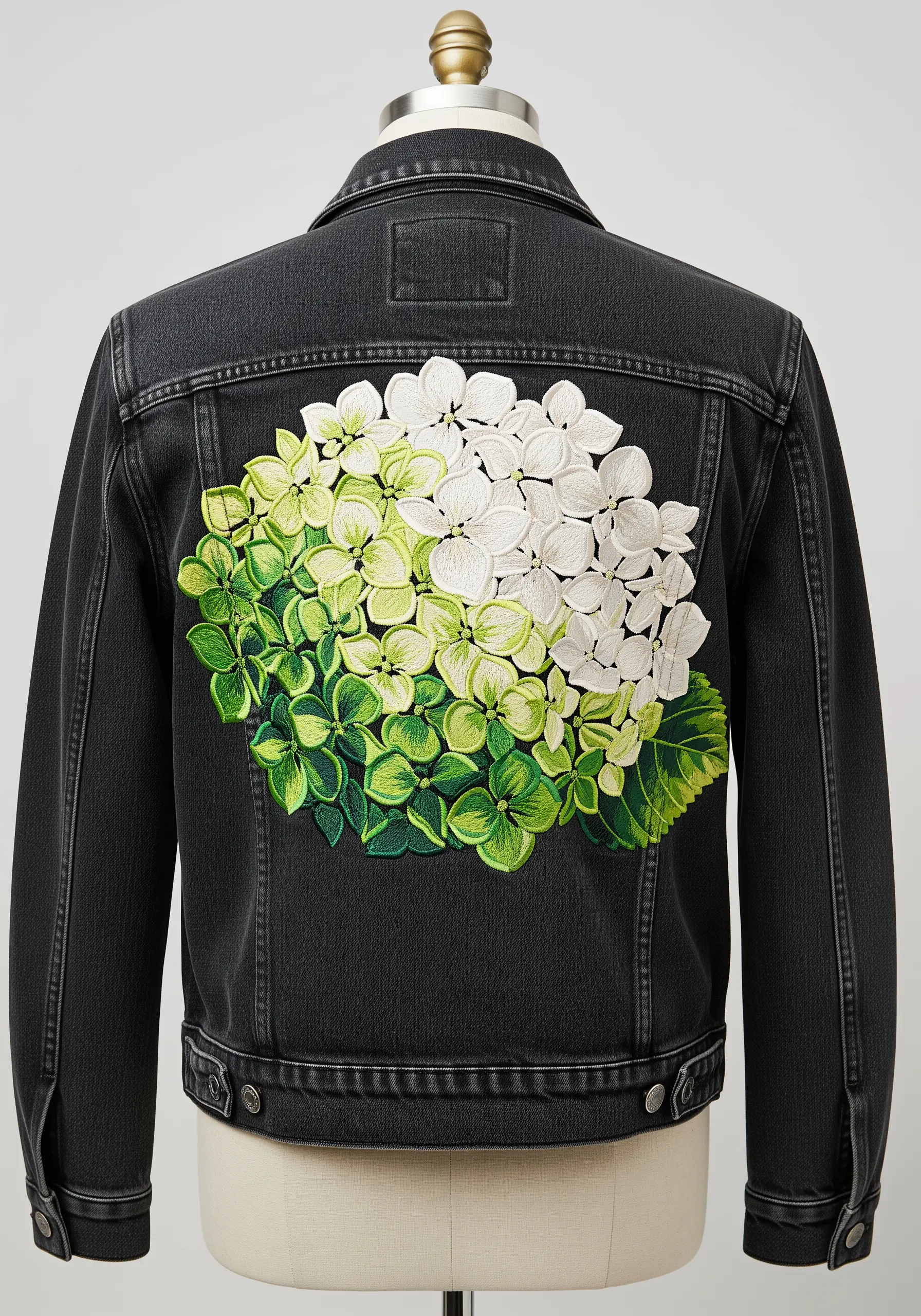 White and green hydrangea embroidered on the back of a black denim jacket.