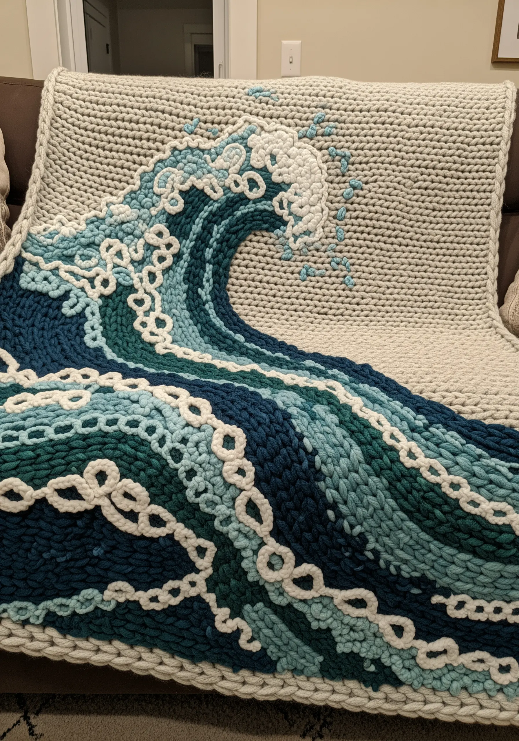 A chunky knit blanket with a large wave design created with different colored chunky yarns.