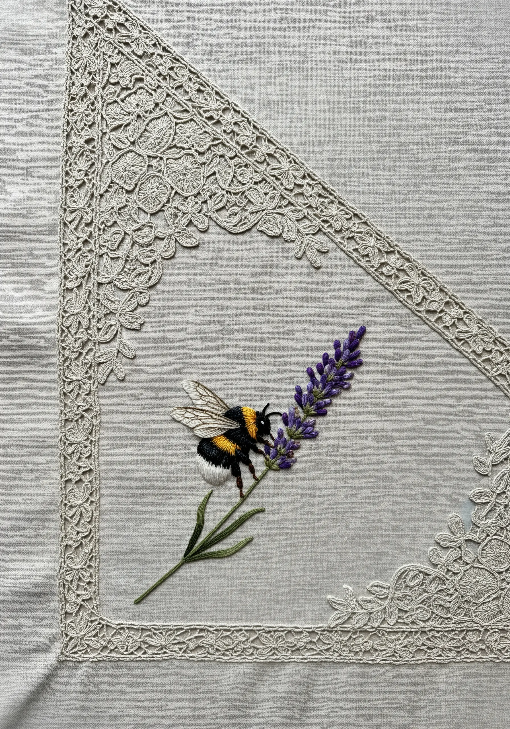 A realistic thread-painted bumblebee on a lavender stem, framed by corner lace.