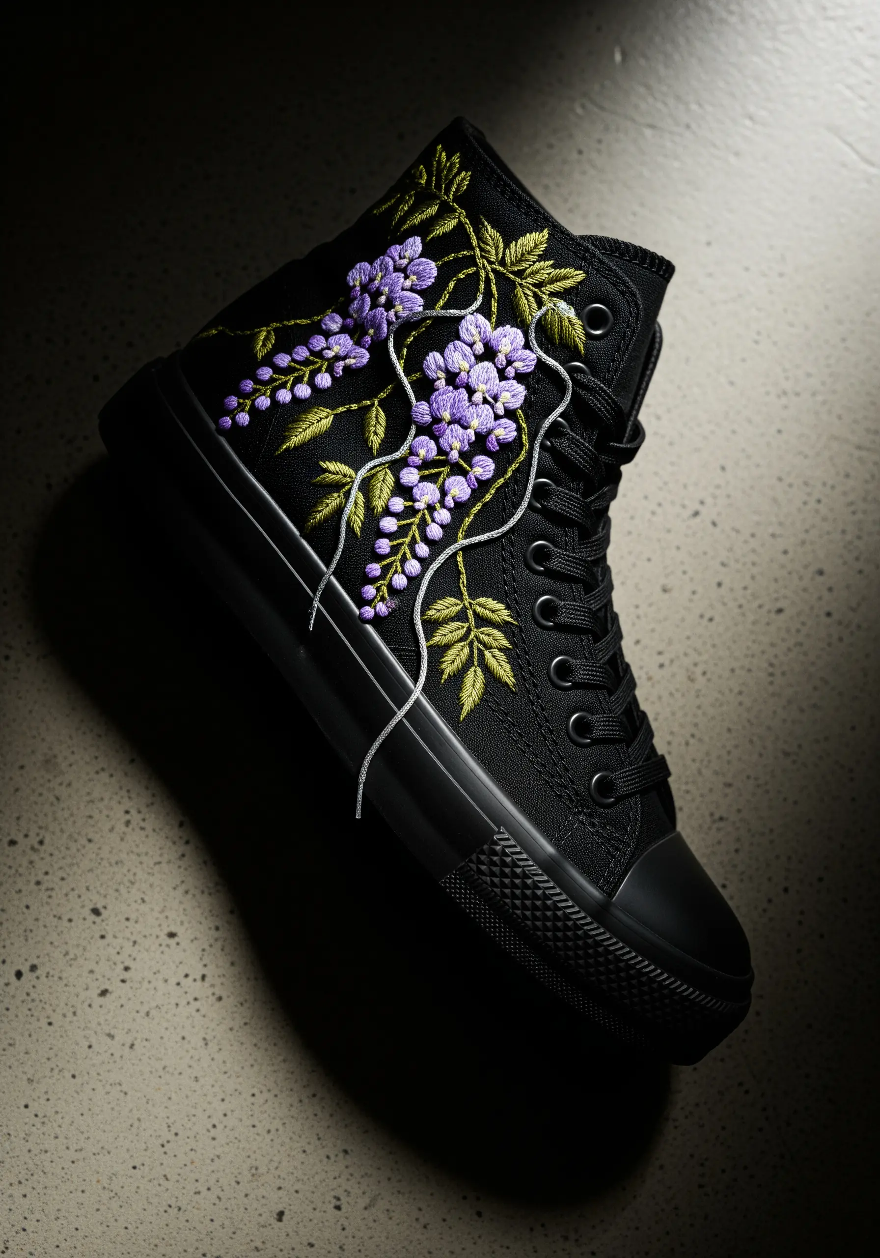 Wisteria flowers embroidered in purple and silver thread on a black high-top sneaker.