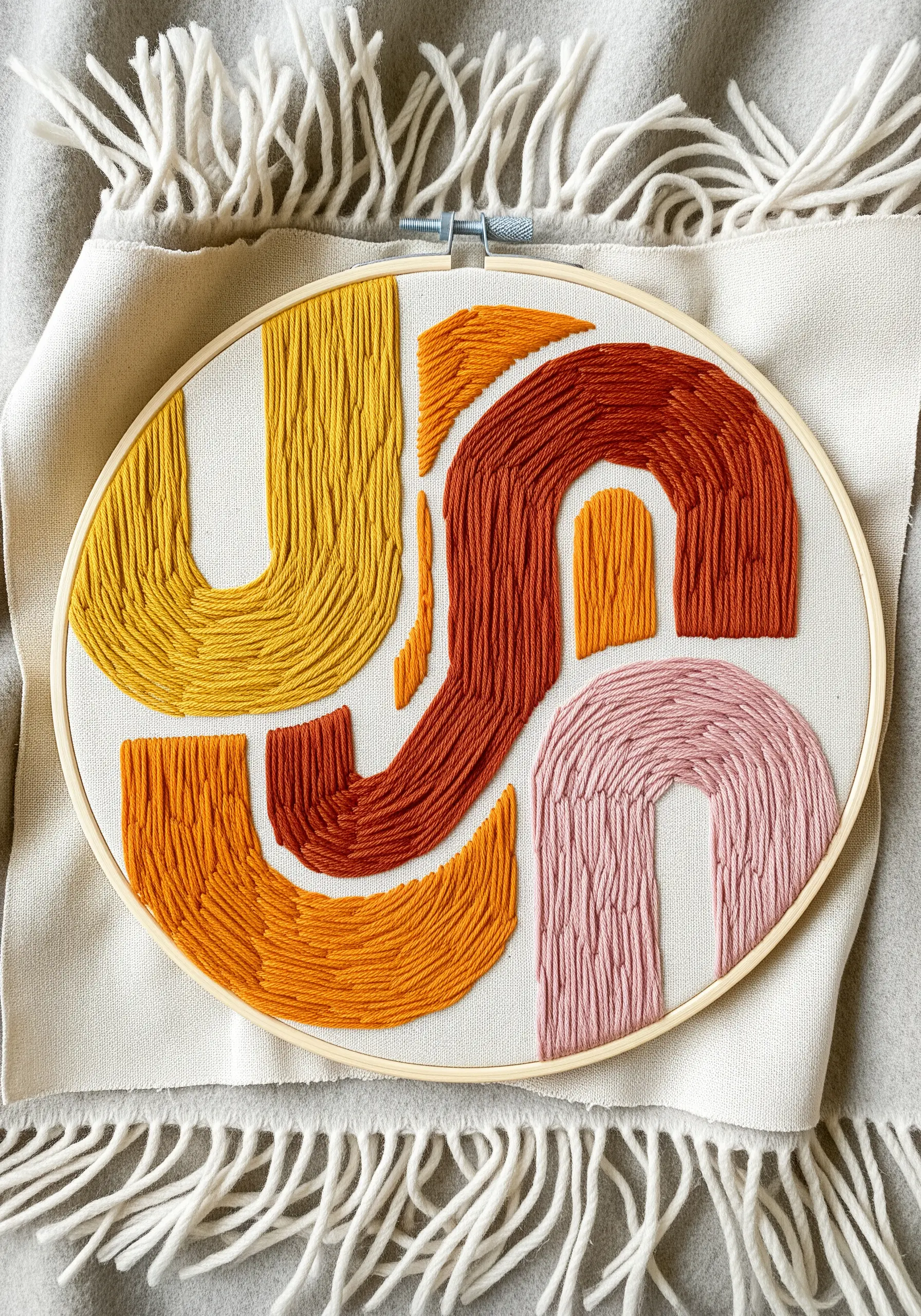 Abstract shapes in warm tones of yellow, orange, and pink, filled with directional satin stitches.