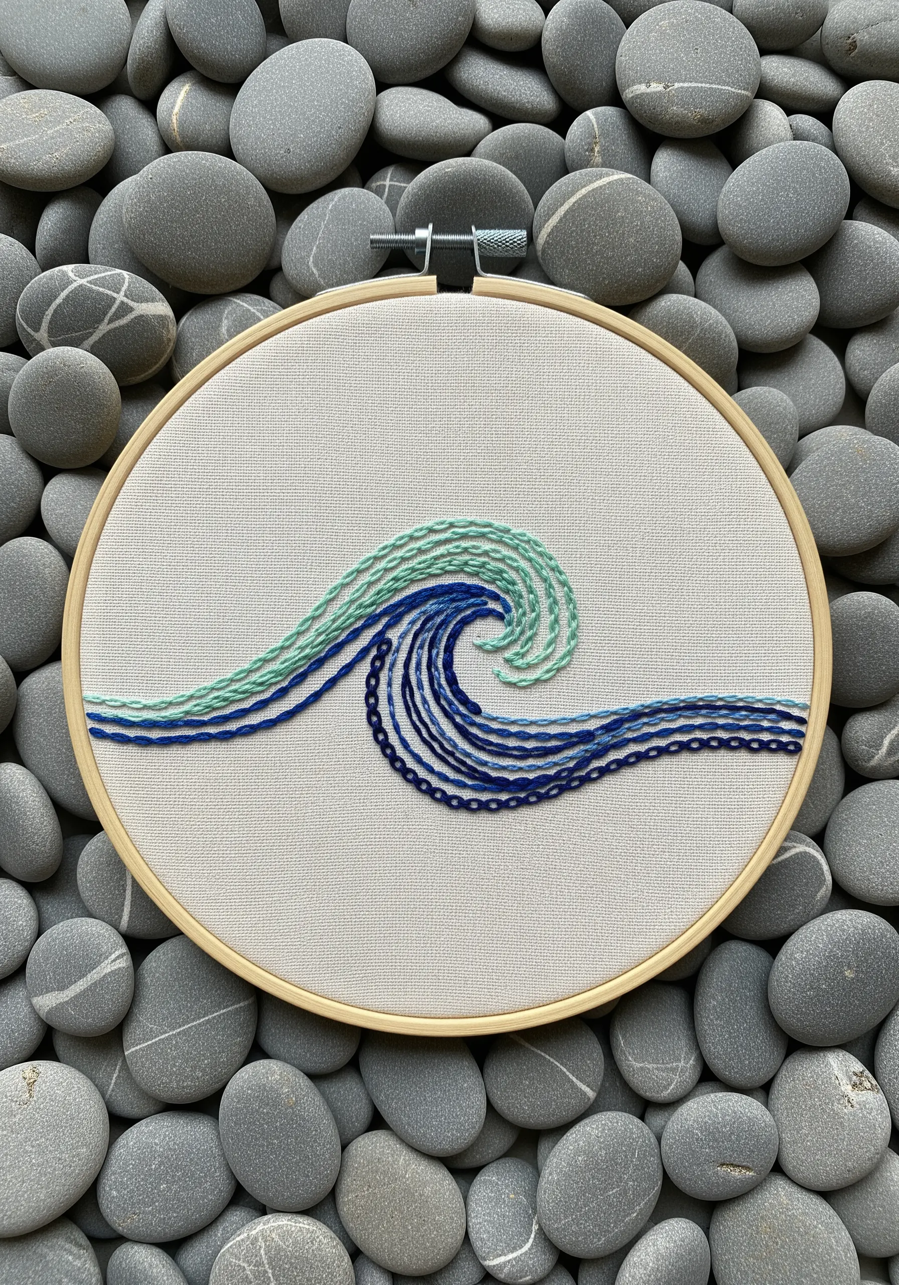 An embroidered wave made of couched lines in shades of blue and sea green.