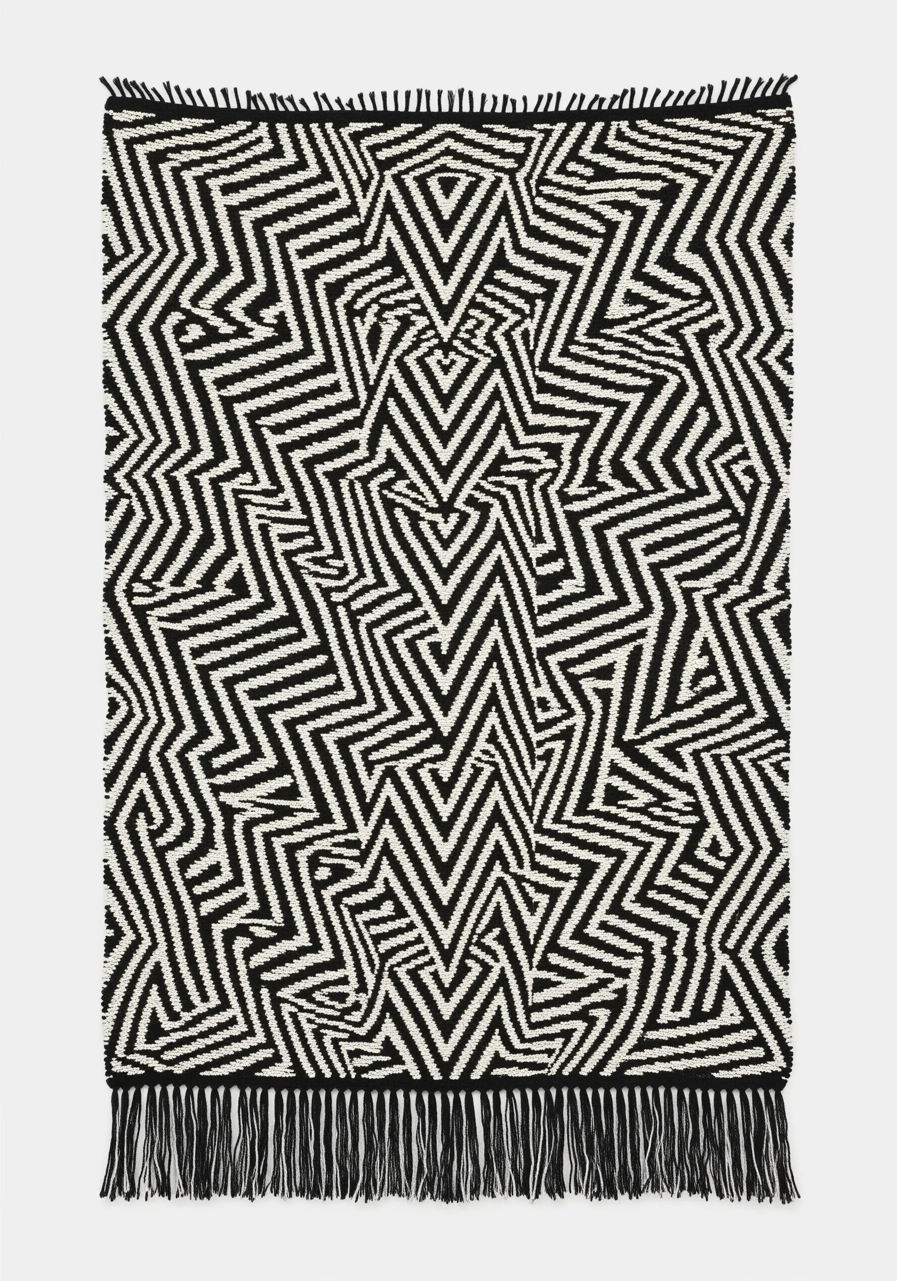 A black-and-white woven wall hanging with a complex, dizzying geometric pattern creating an optical illusion.