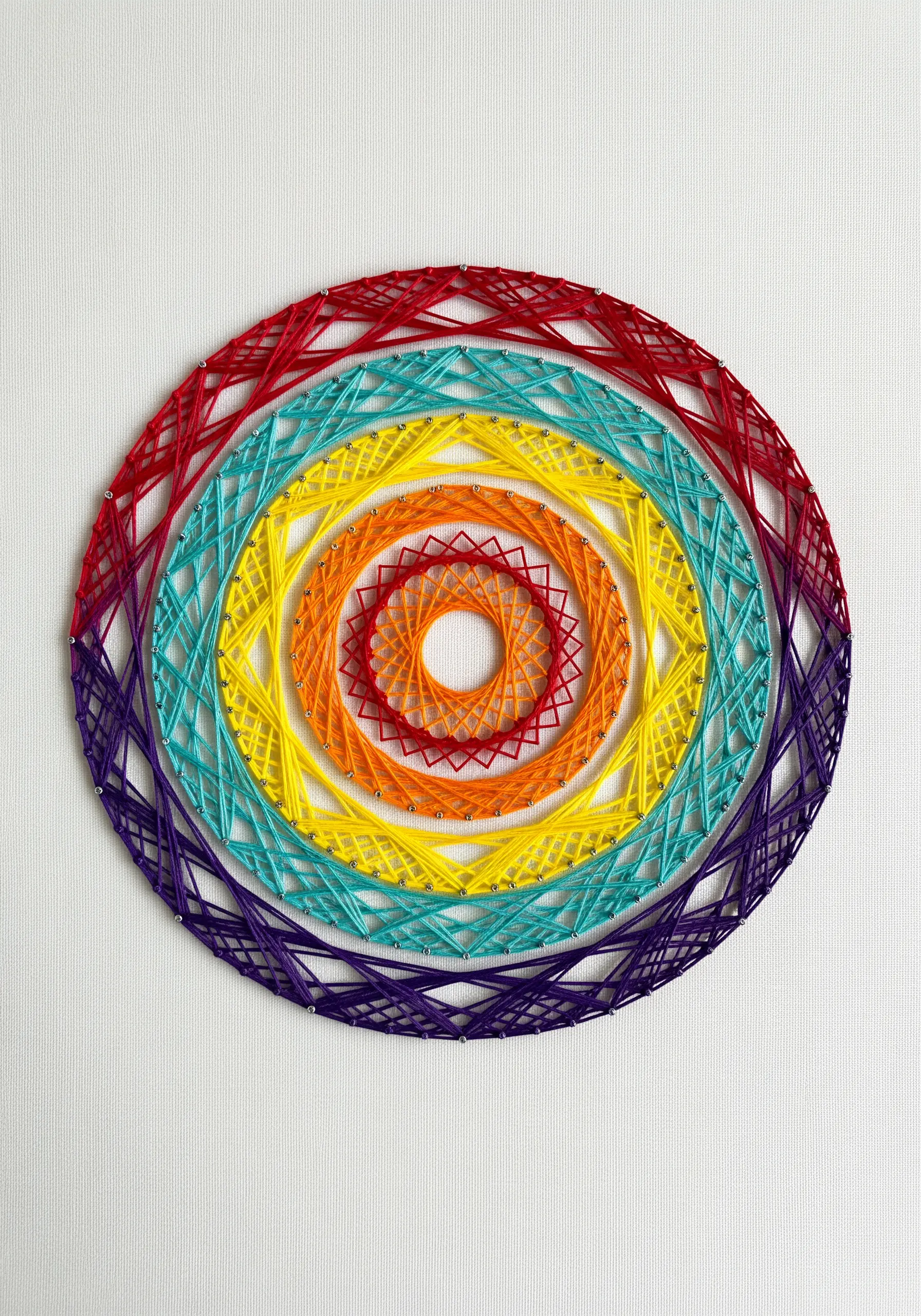 String art with concentric rainbow-colored ellipses creating an optical illusion.