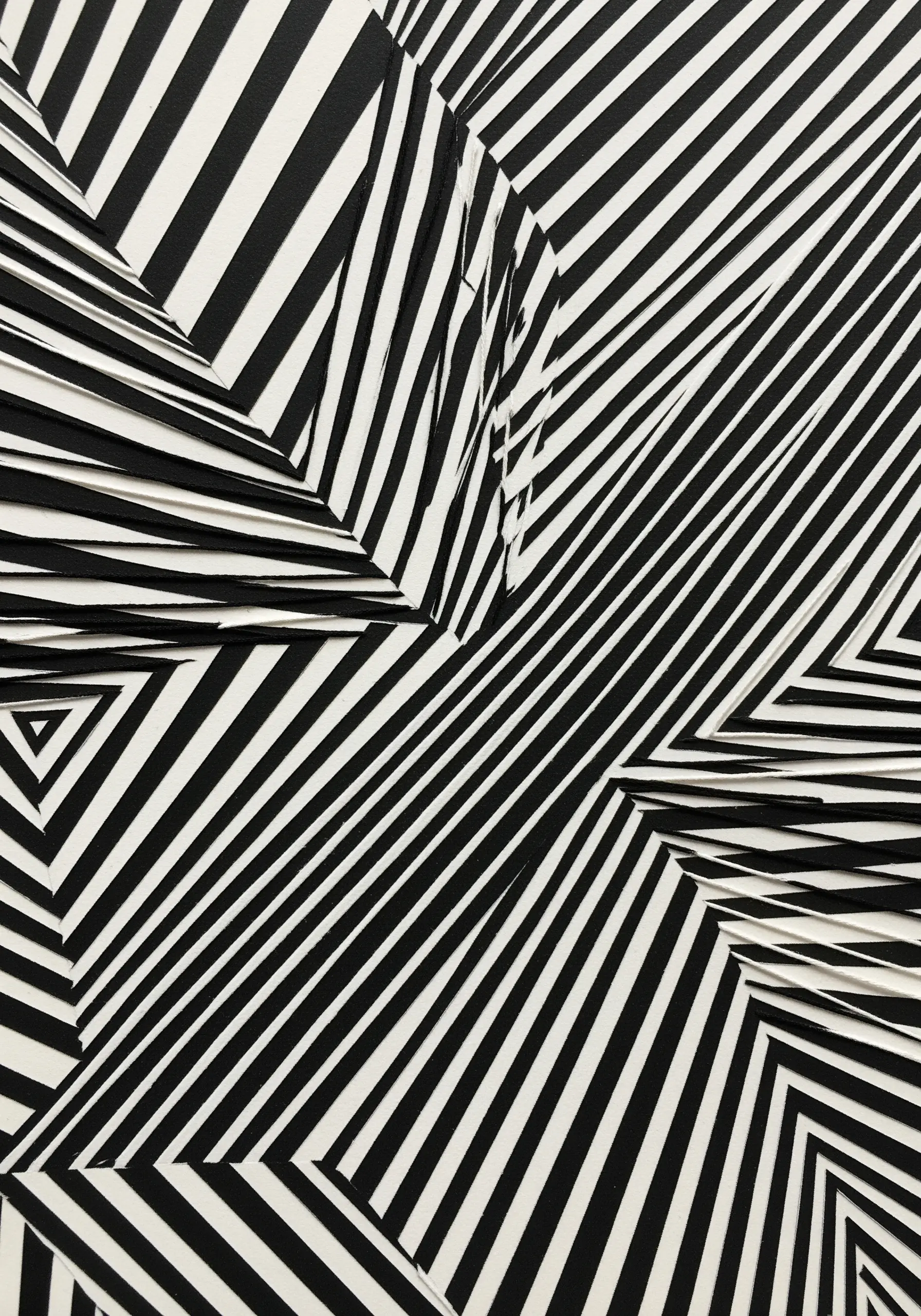 An abstract collage made from black-and-white striped fabric cut and arranged to create an optical illusion.