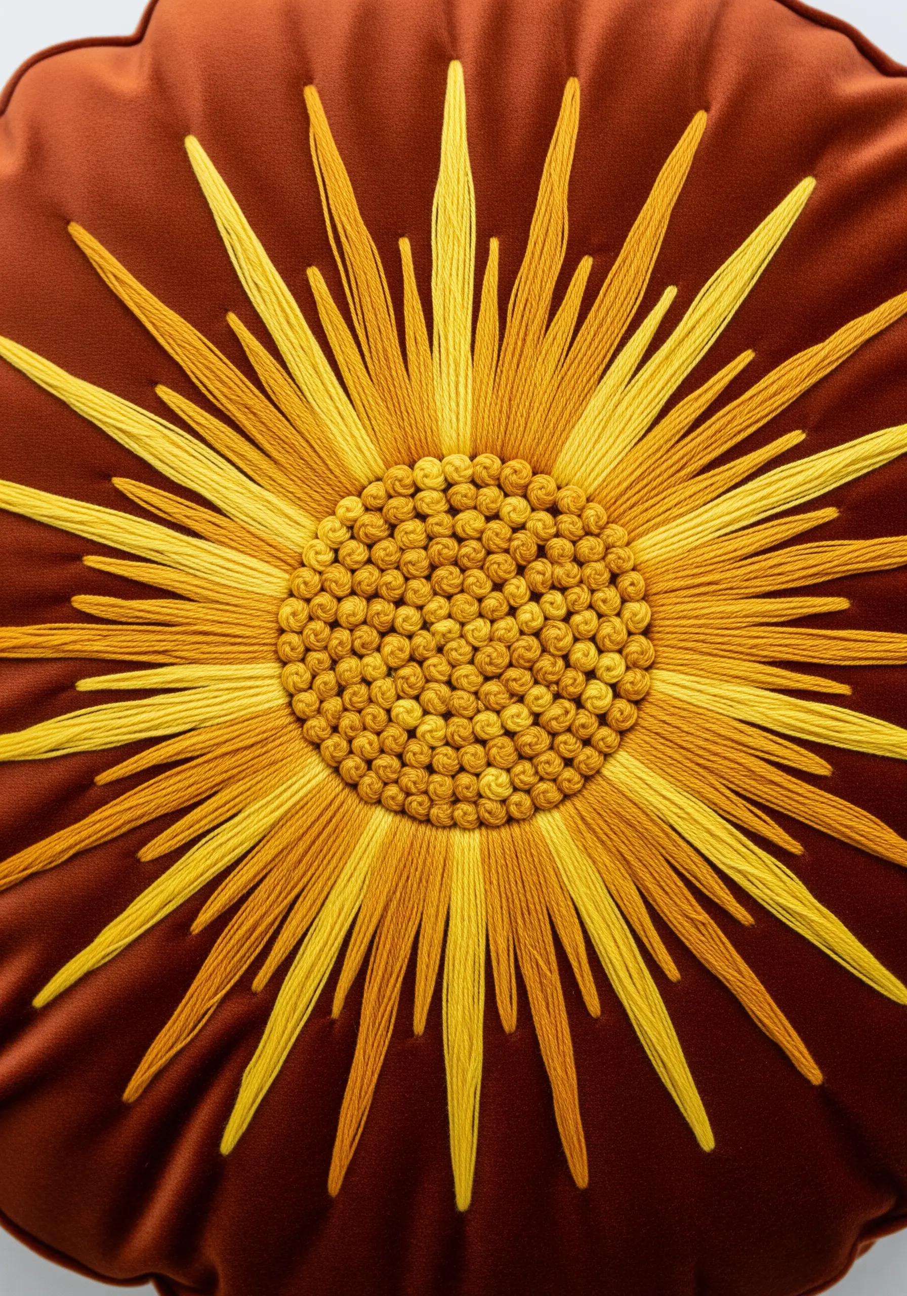 Embroidered sunburst with long straight stitches in yellow and orange gradients on velvet.
