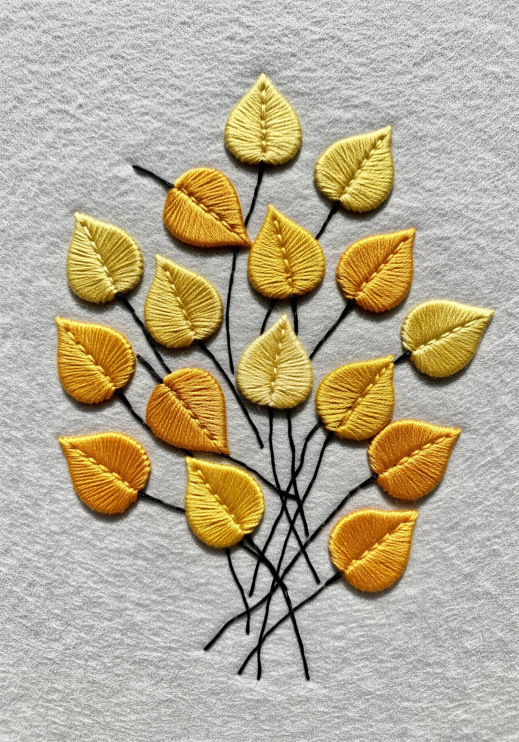 A cluster of small, raised yellow and orange leaves on a light grey fabric.