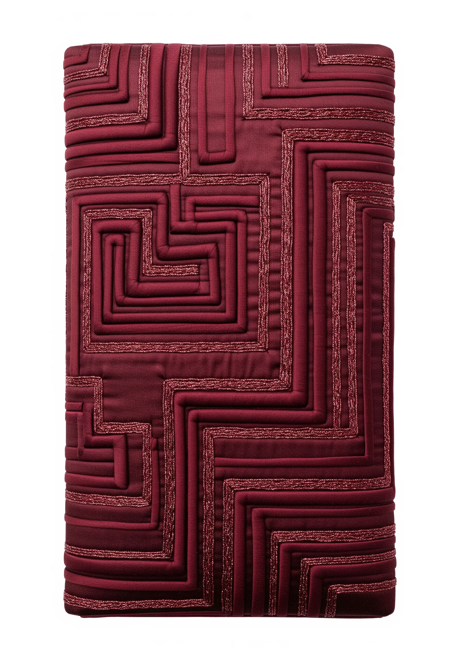 A deep red textile with a geometric labyrinth pattern created with raised trapunto channels.