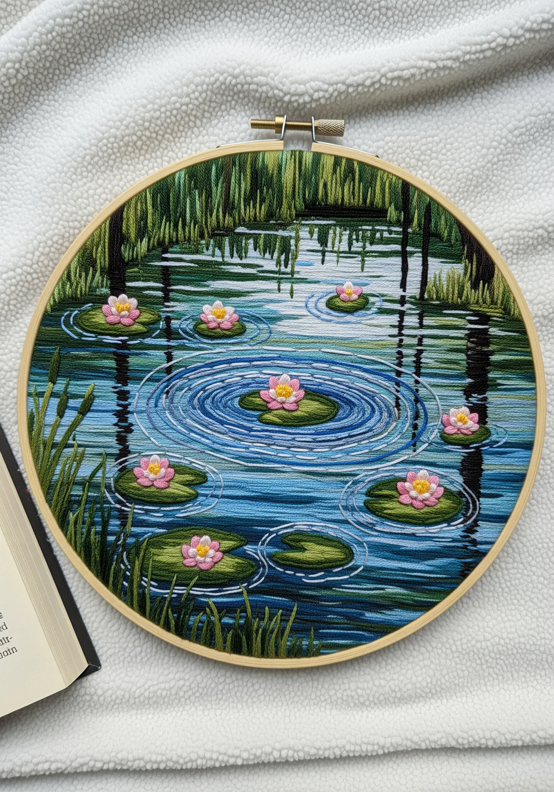 Embroidery hoop art of a water lily pond with reflections and ripples in the water.