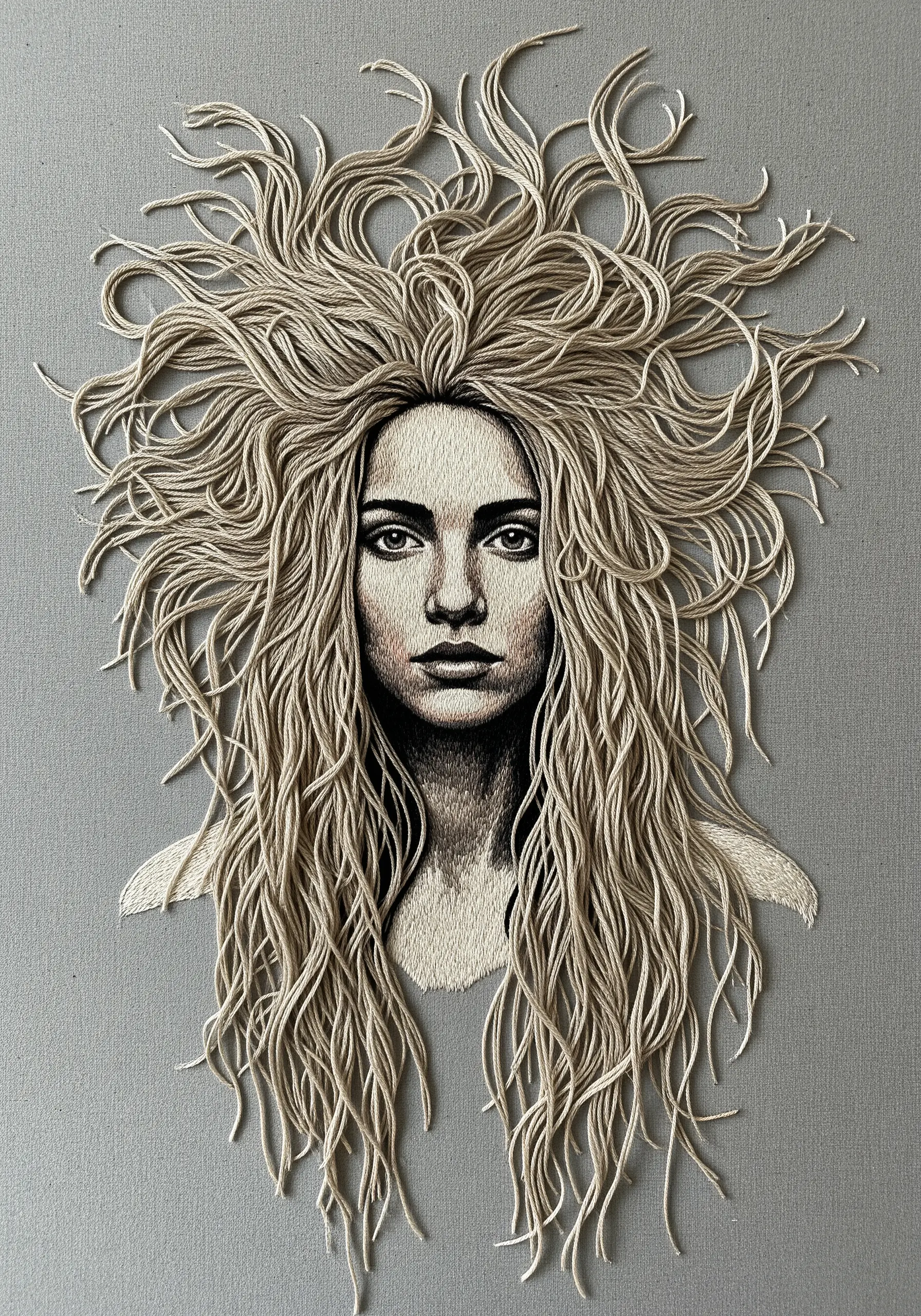 An embroidered portrait where the woman's long hair is made of loose, three-dimensional thread.