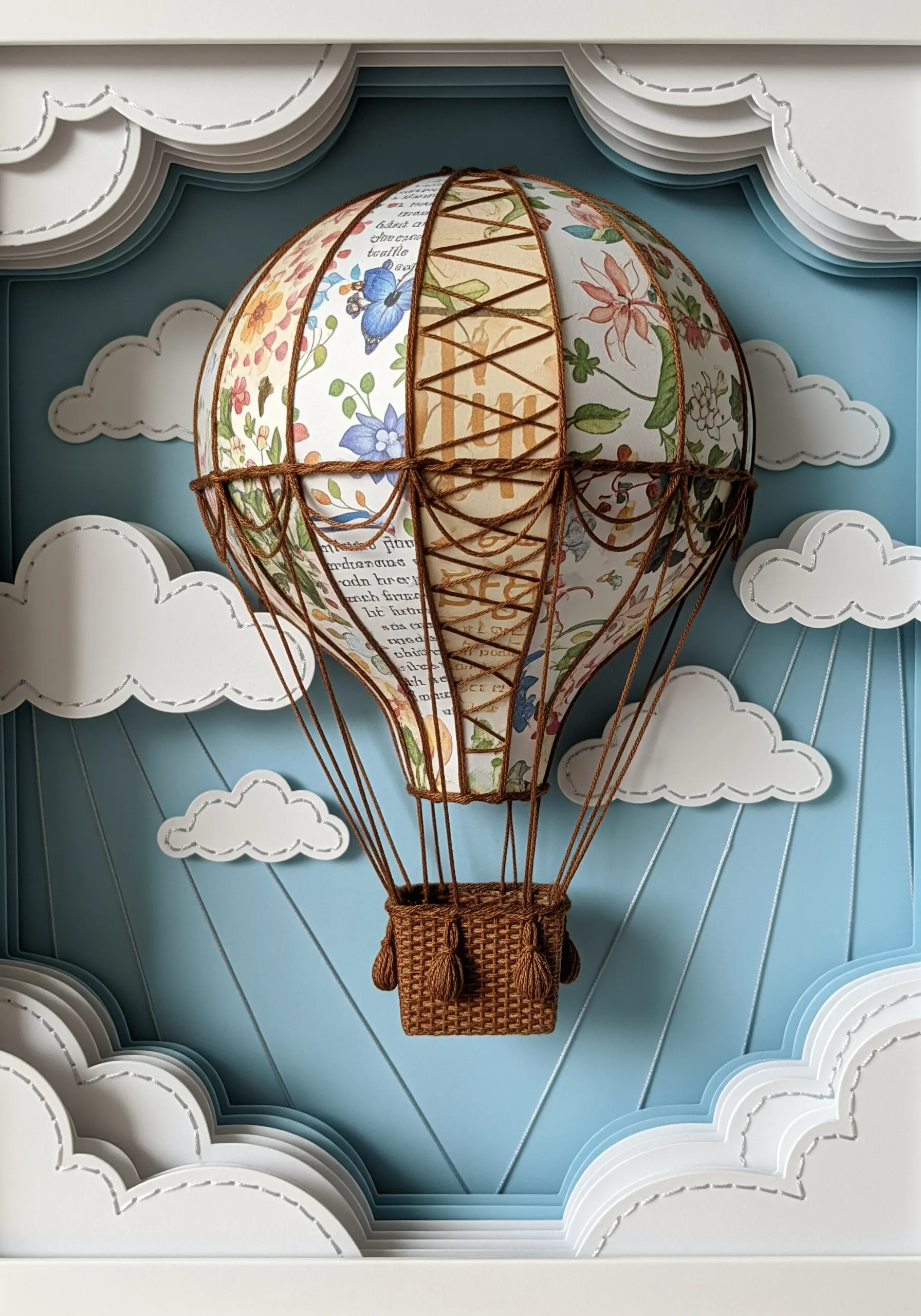 A 3D paper hot air balloon with brown embroidery cording used for the rigging and basket details.