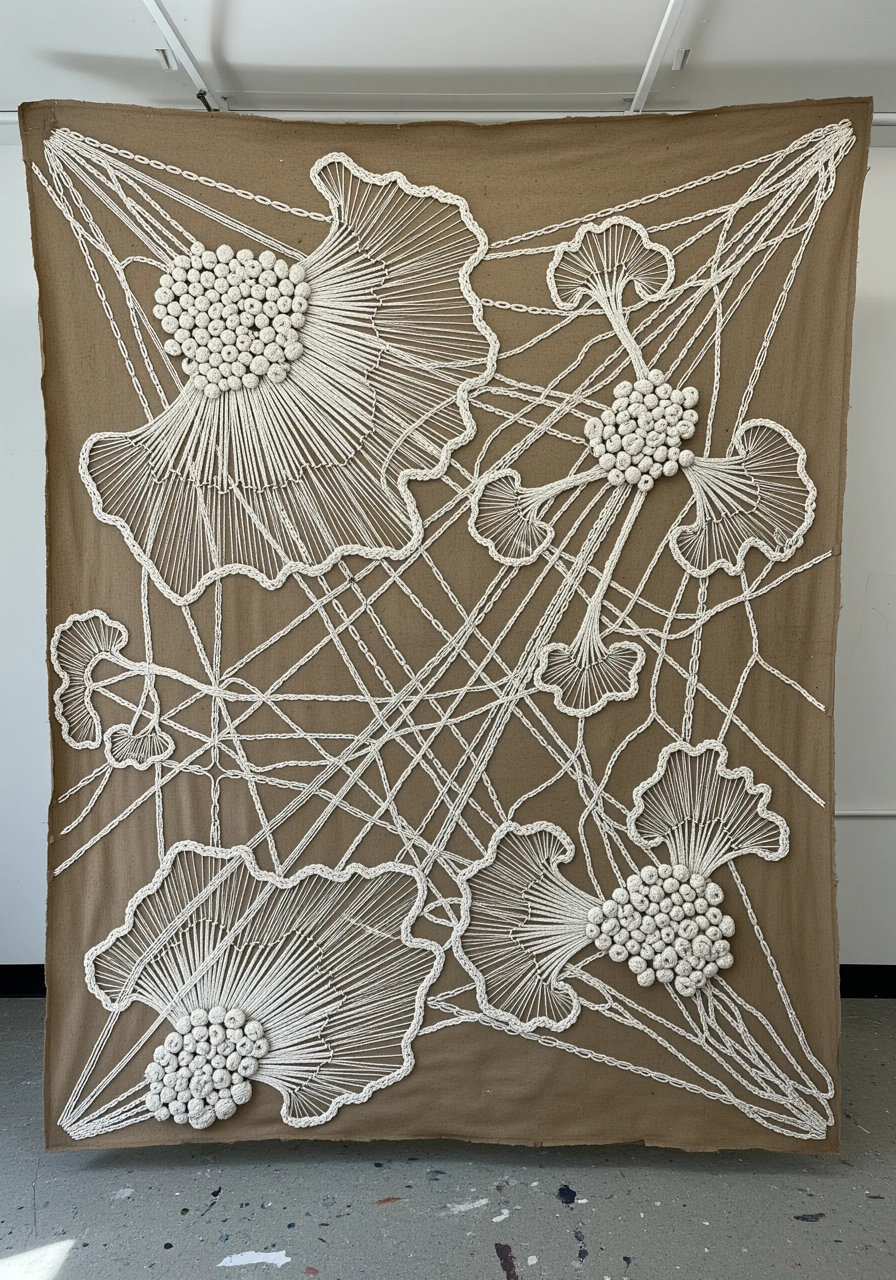 Large-scale string art embroidery of ginkgo leaves on a brown canvas.