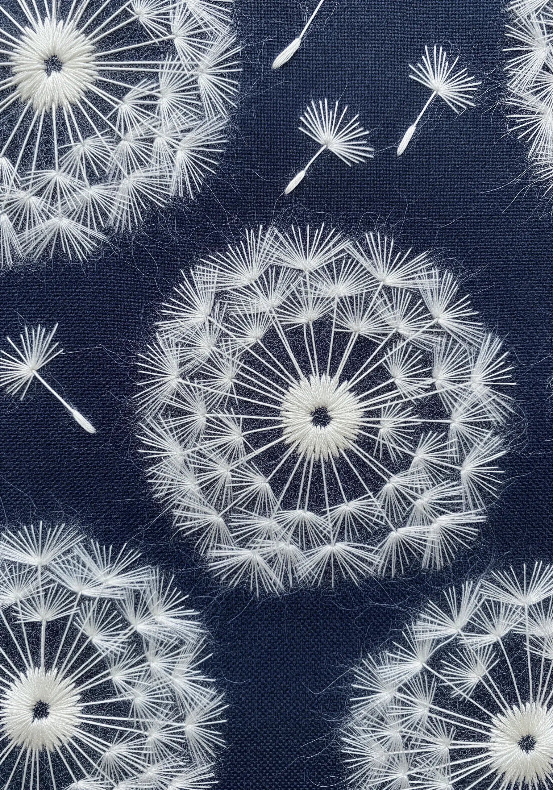 Dandelion clocks embroidered on navy fabric, with frayed thread ends creating a fluffy effect.