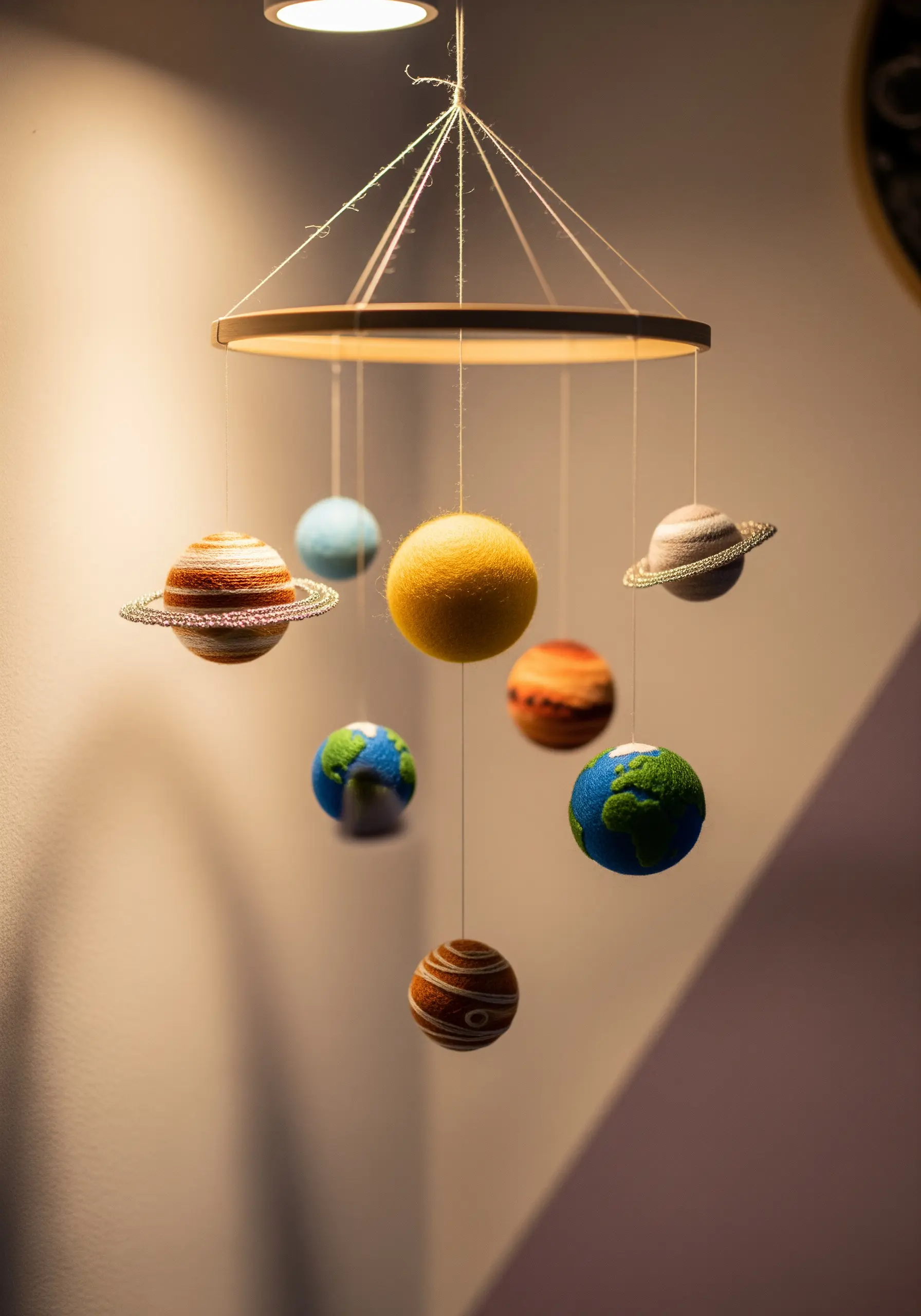 A nursery mobile of the solar system, with planets made from wrapped yarn and felt.