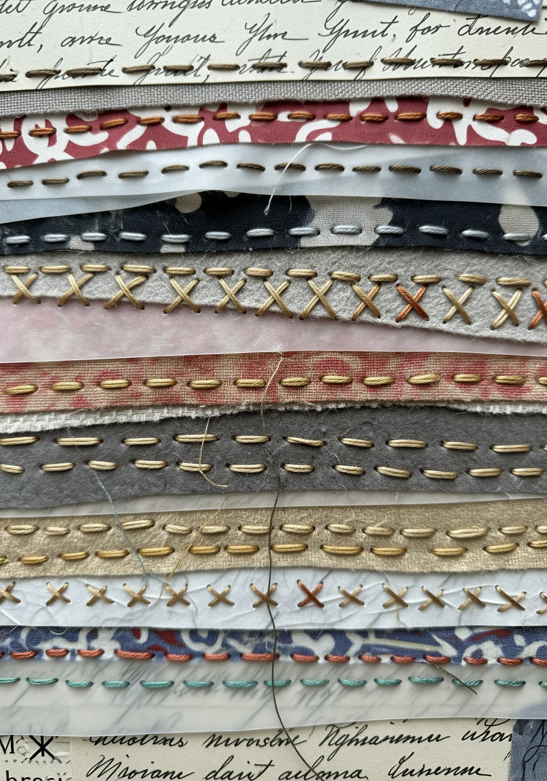 A layered collage of paper and fabric scraps held together with decorative embroidery stitches.