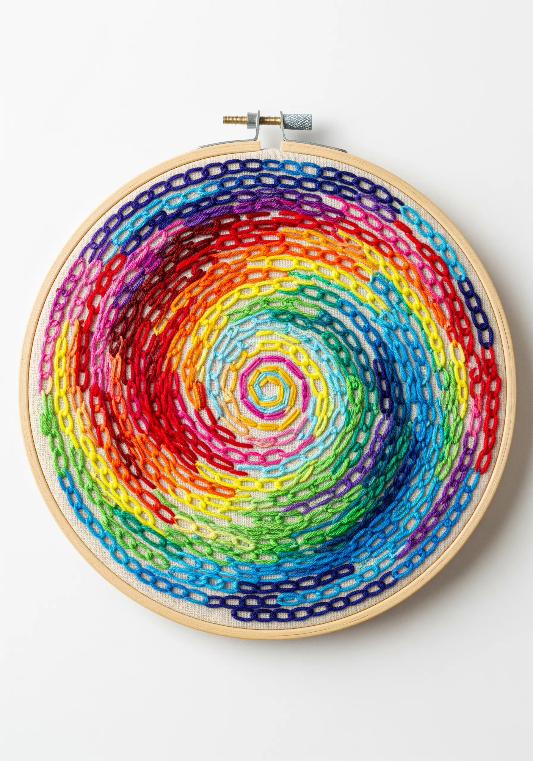 A vibrant spiral of rainbow-colored chain stitches filling an embroidery hoop.