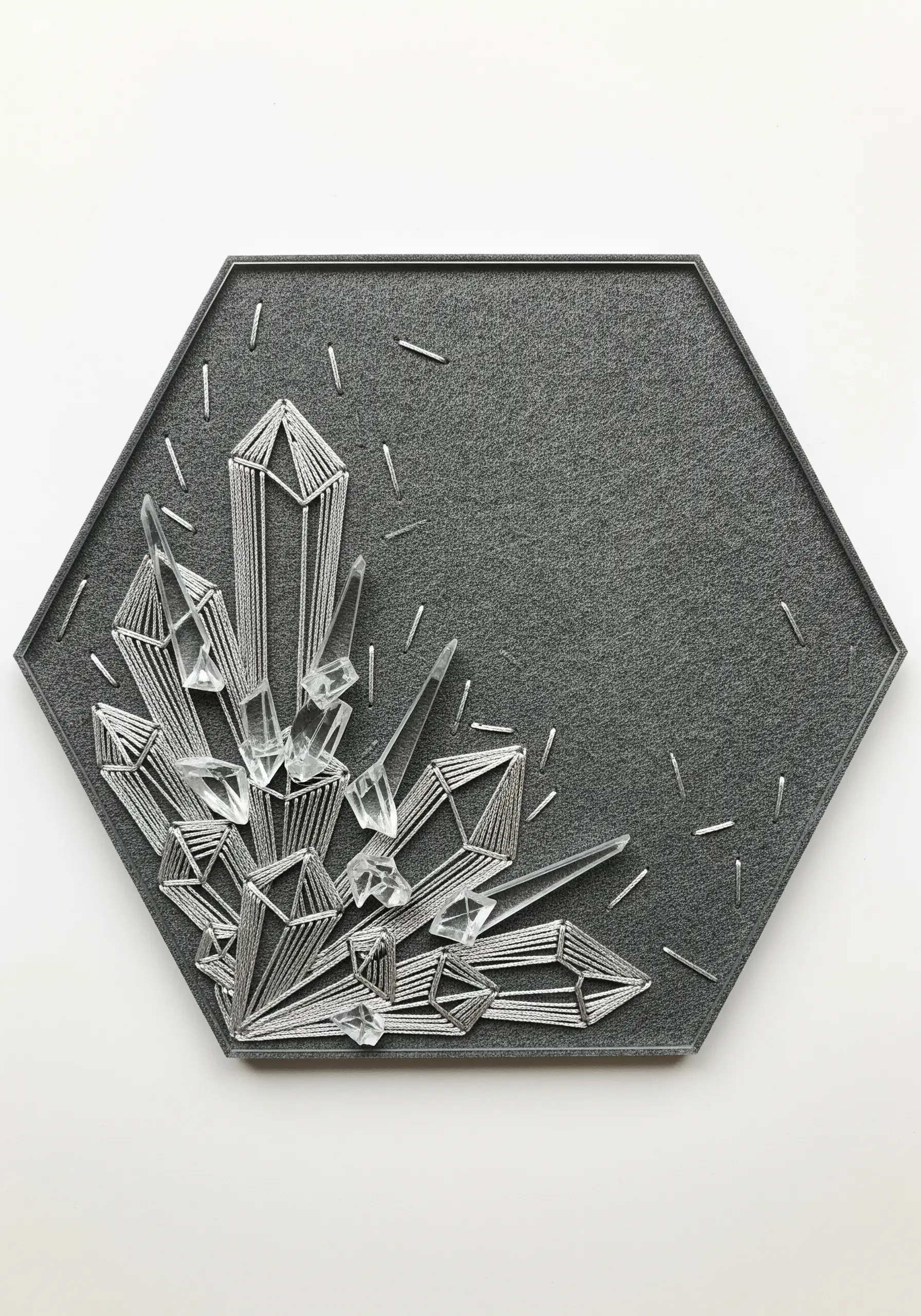 String art crystal formation with silver thread and clear acrylic shards on a gray hexagonal board.