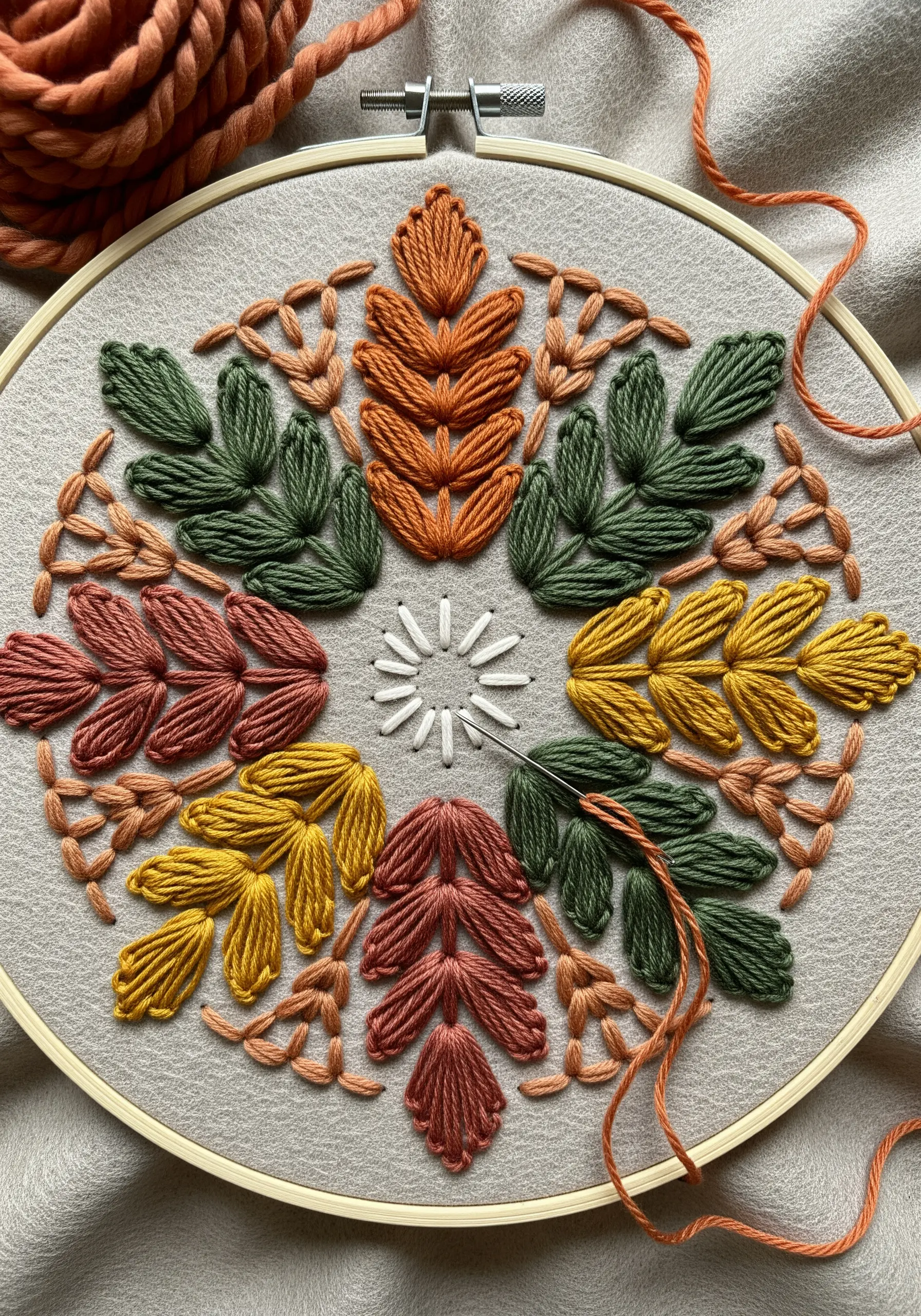 A circular arrangement of embroidered leaves in autumn colors creating a mandala.