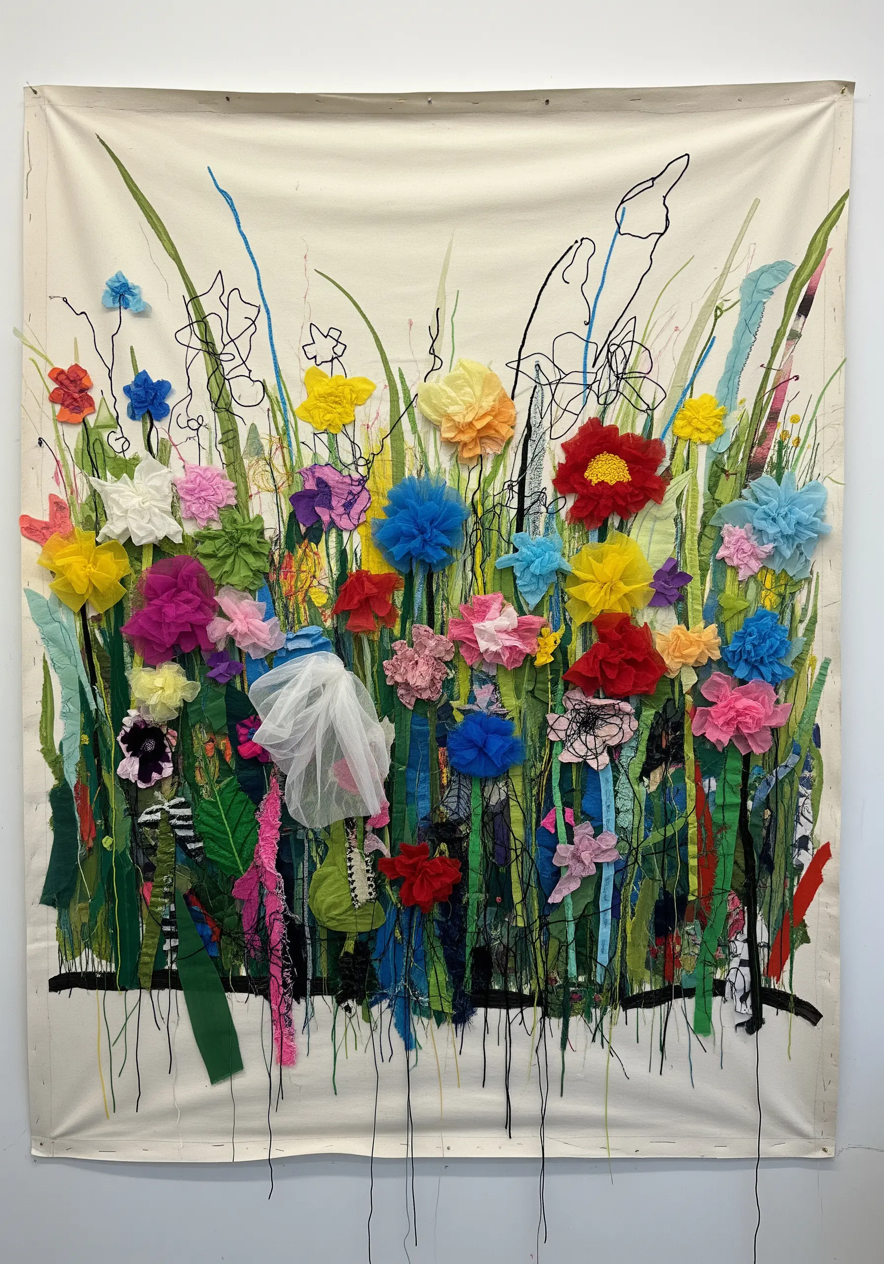 A large, vibrant wall hanging of a wildflower meadow using 3D fabric flowers and loose threads