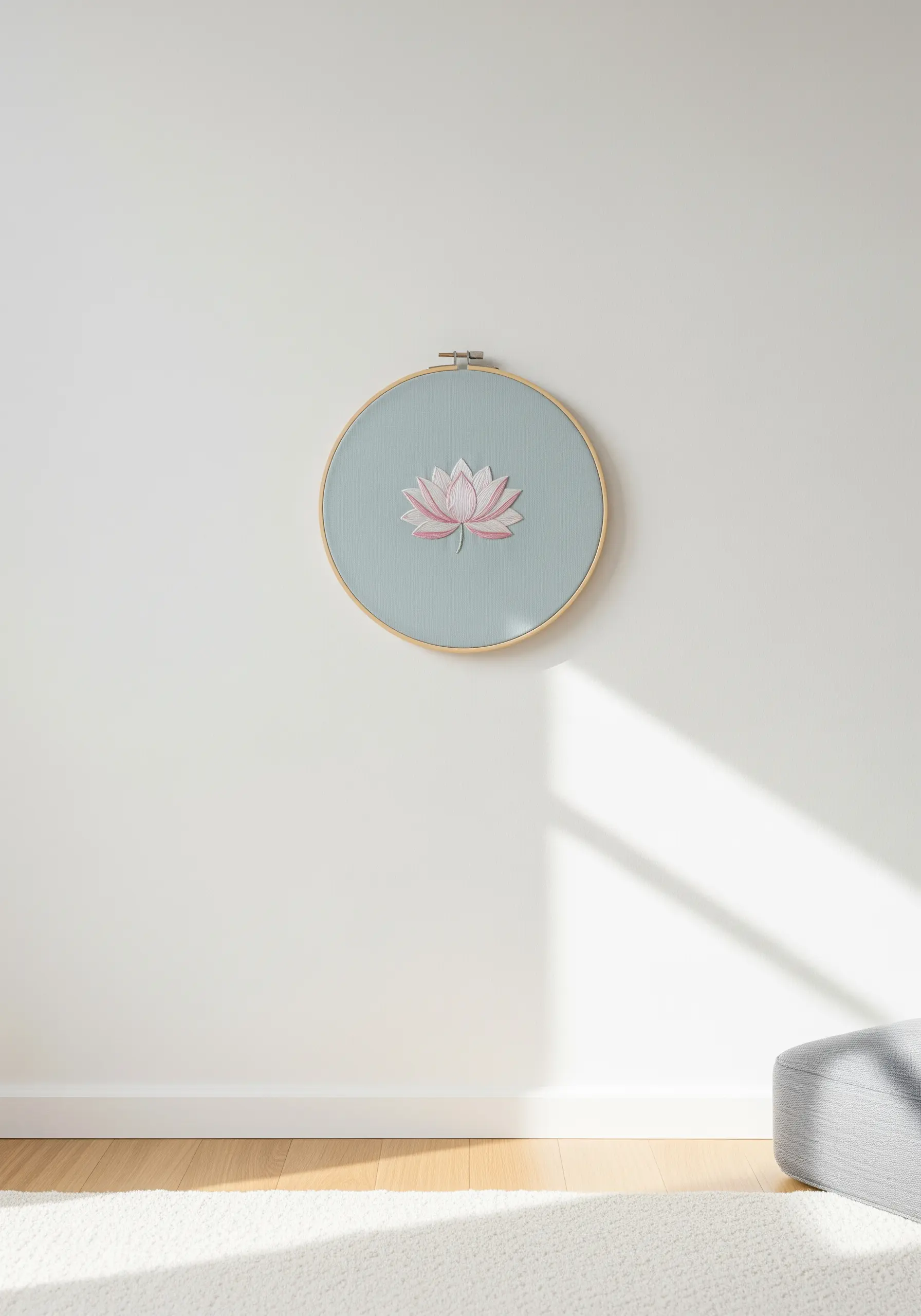 A single, minimalist lotus flower embroidered in the center of a hoop on a pale blue background.