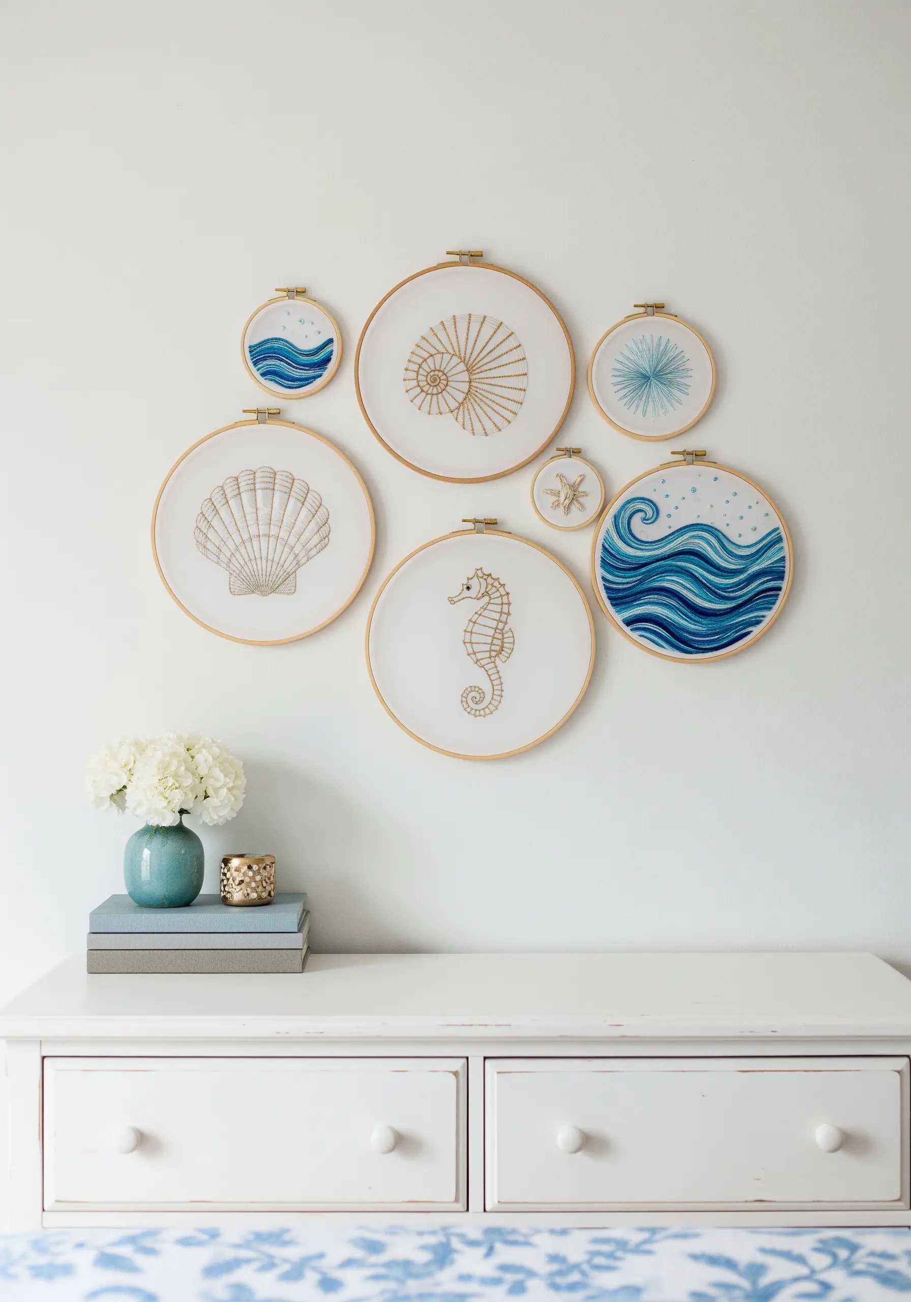A gallery wall of seven embroidery hoops with various coastal motifs like shells, waves, and a seahorse.