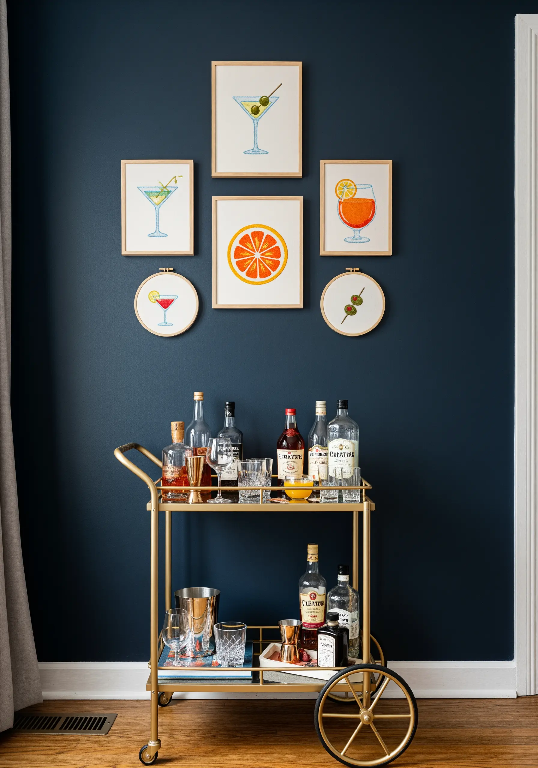 A gallery wall of framed and hooped embroidery featuring various cocktails above a bar cart