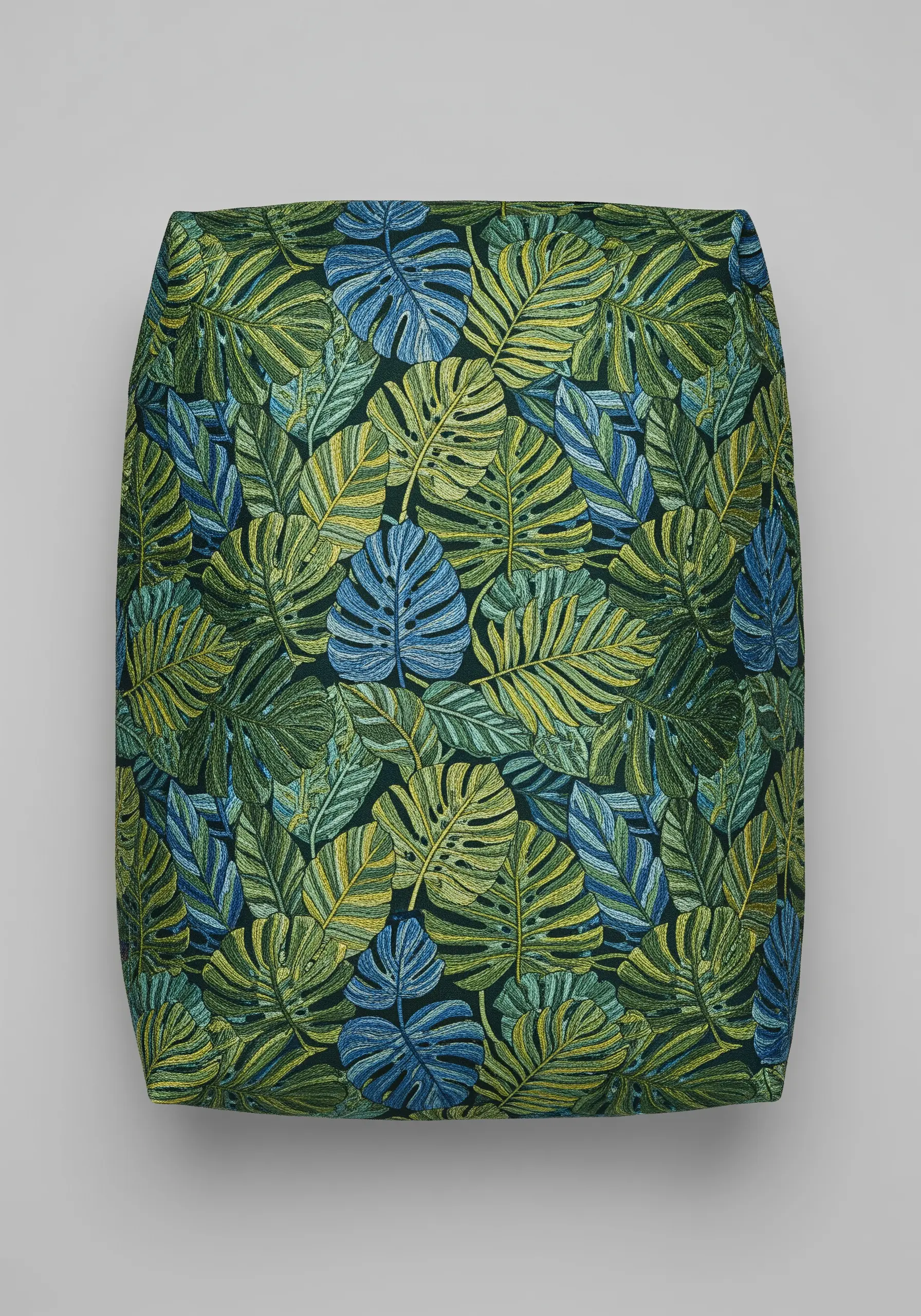 A dense, all-over embroidery pattern of monstera and palm leaves in shades of green, blue, and chartreuse.
