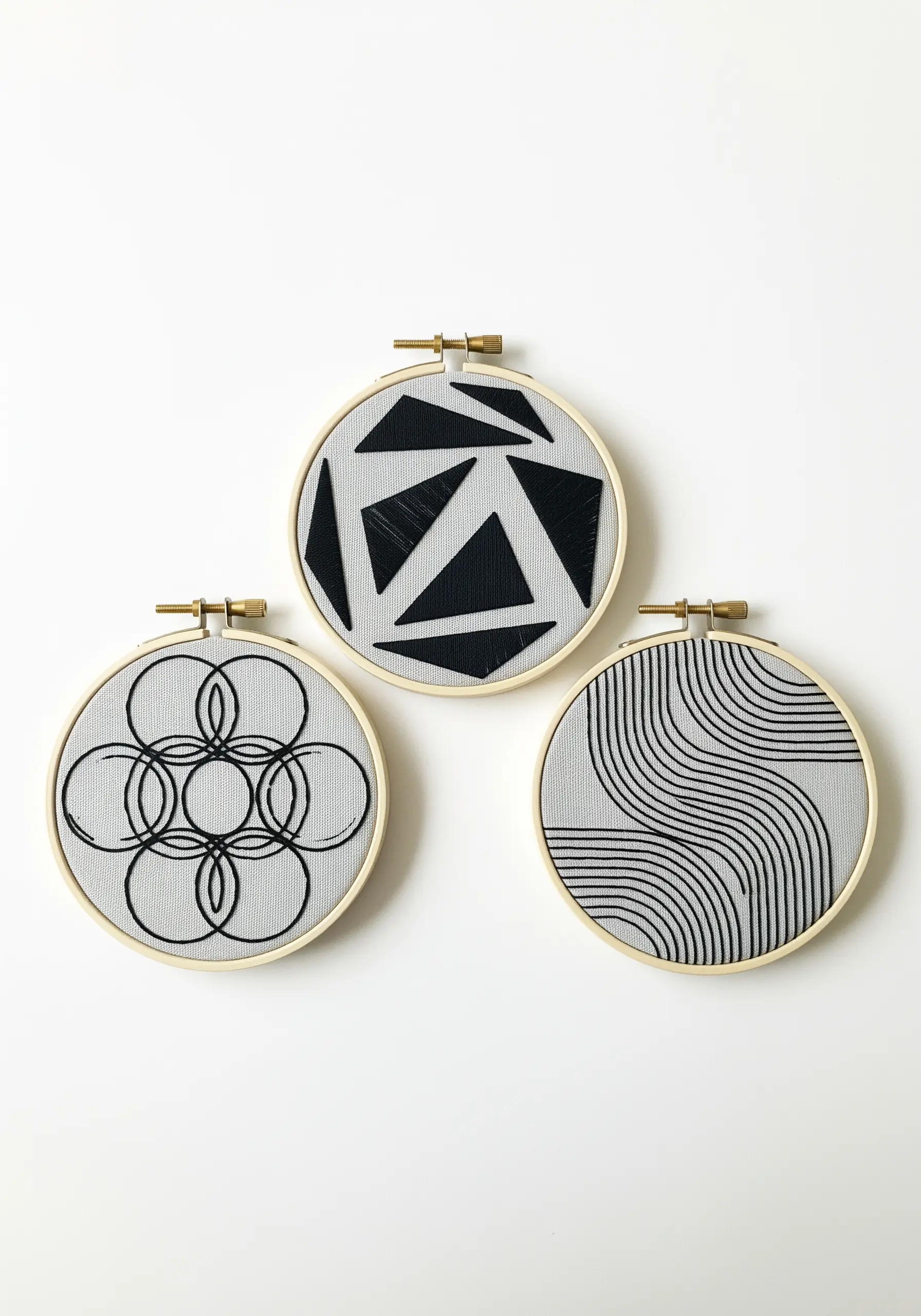 Three small embroidery hoops with abstract black geometric patterns.