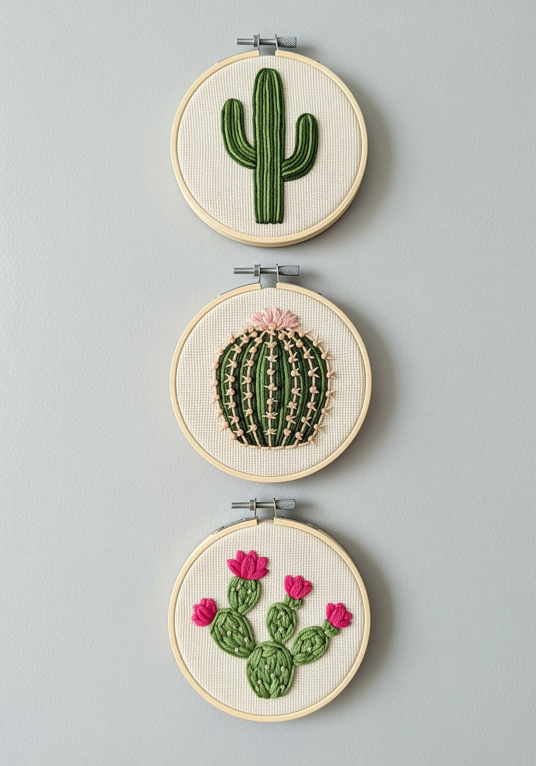 A triptych of three small hoops, each with a different embroidered cactus.