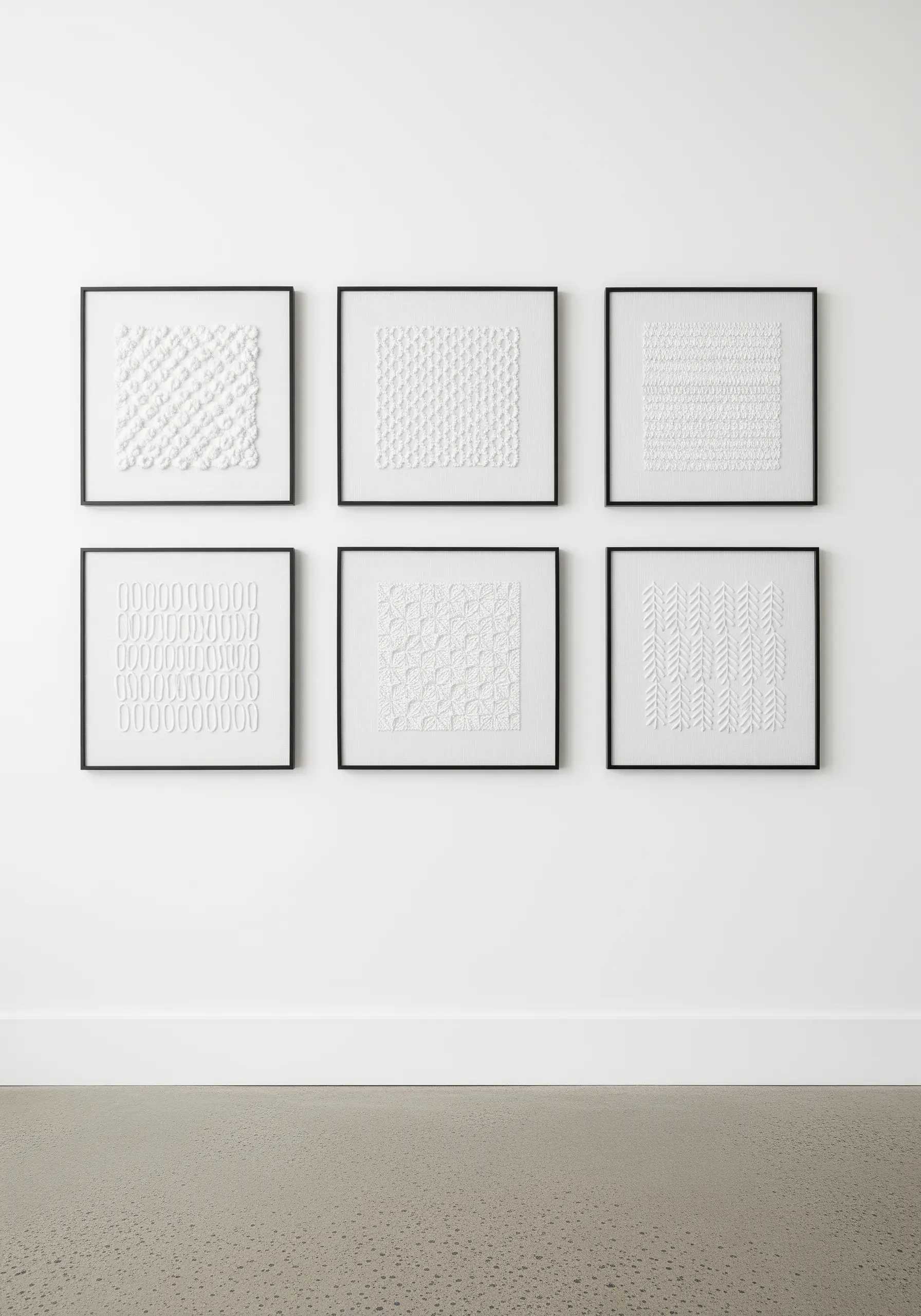 A gallery wall of six framed white-on-white embroidery samplers showing different textures.