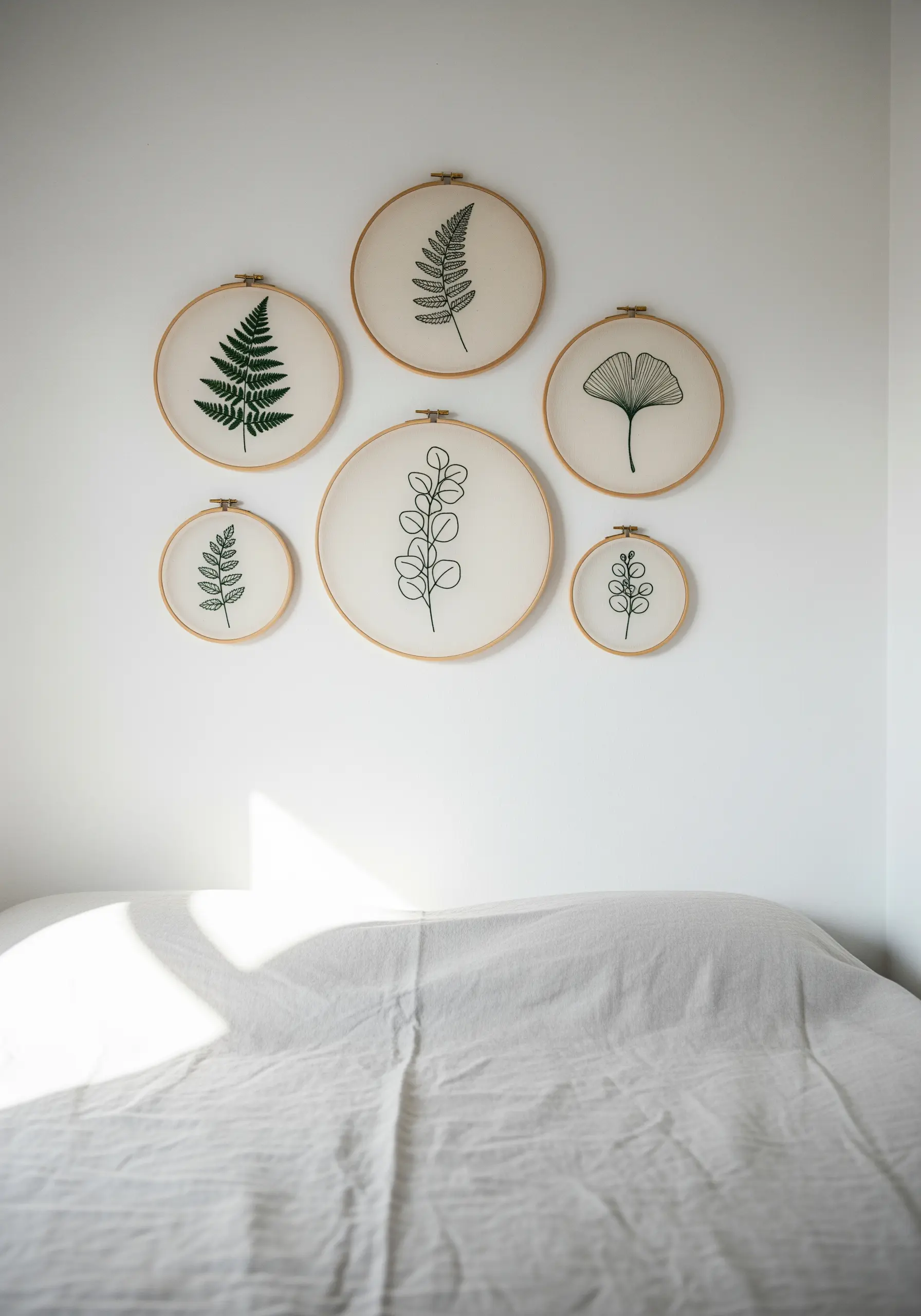 A gallery wall of six embroidery hoops with minimalist black thread leaf designs