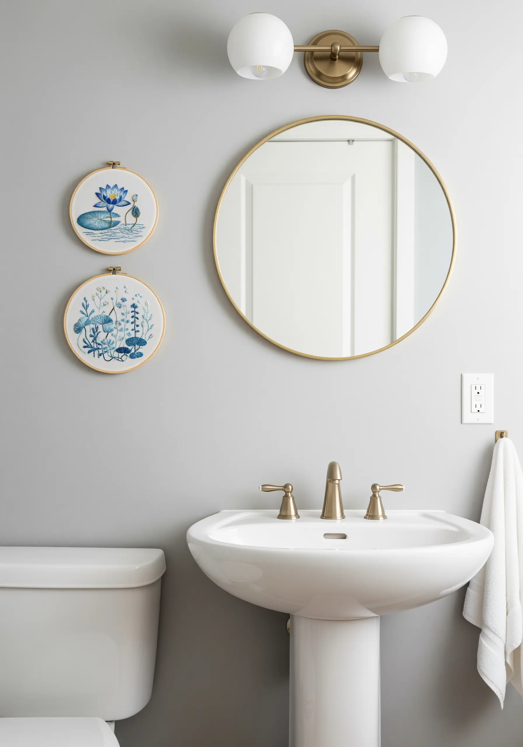 Two embroidery hoops with water lily and aquatic plant designs hanging in a modern bathroom.