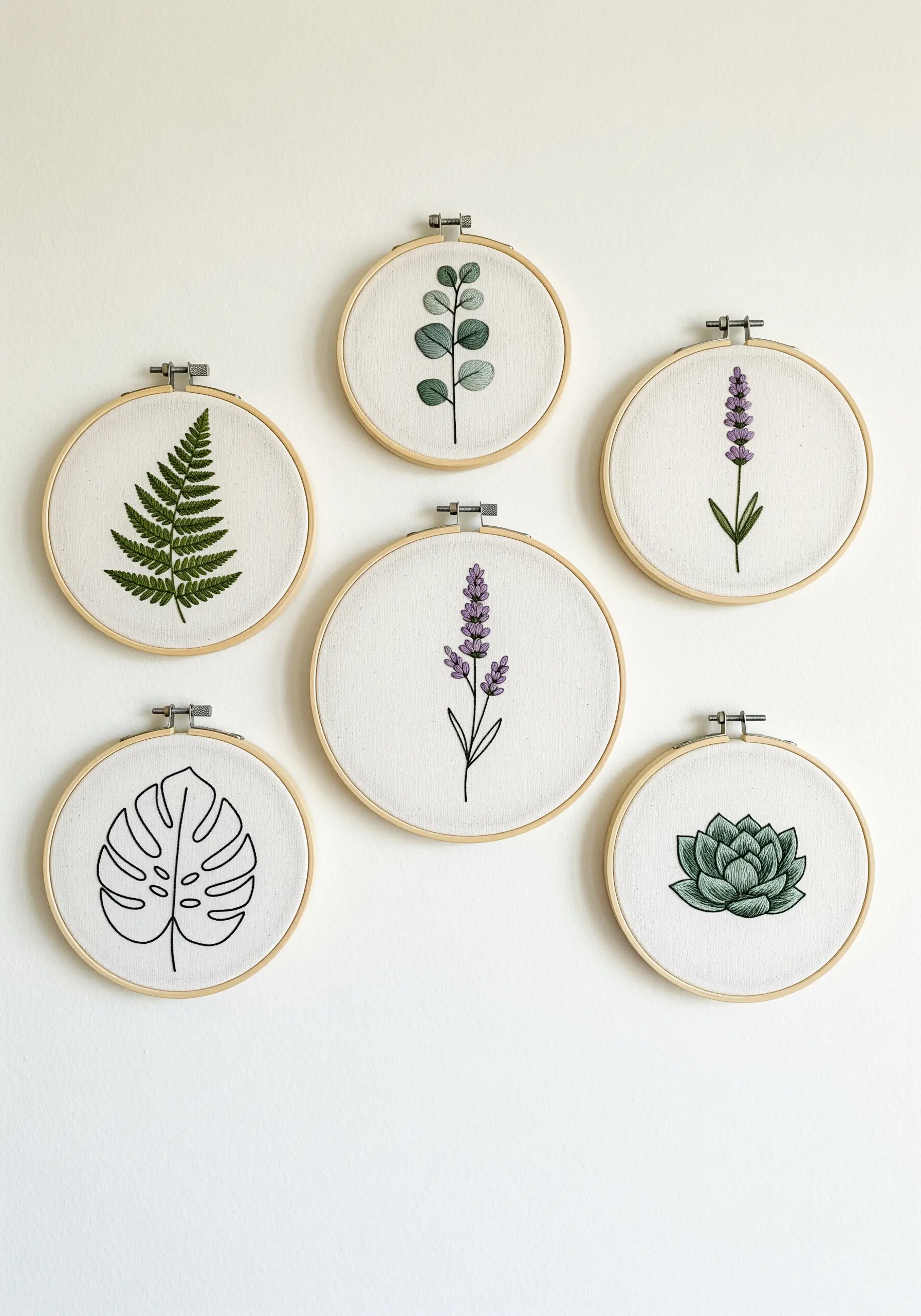 A collection of six small embroidery hoops, each featuring a different botanical illustration.