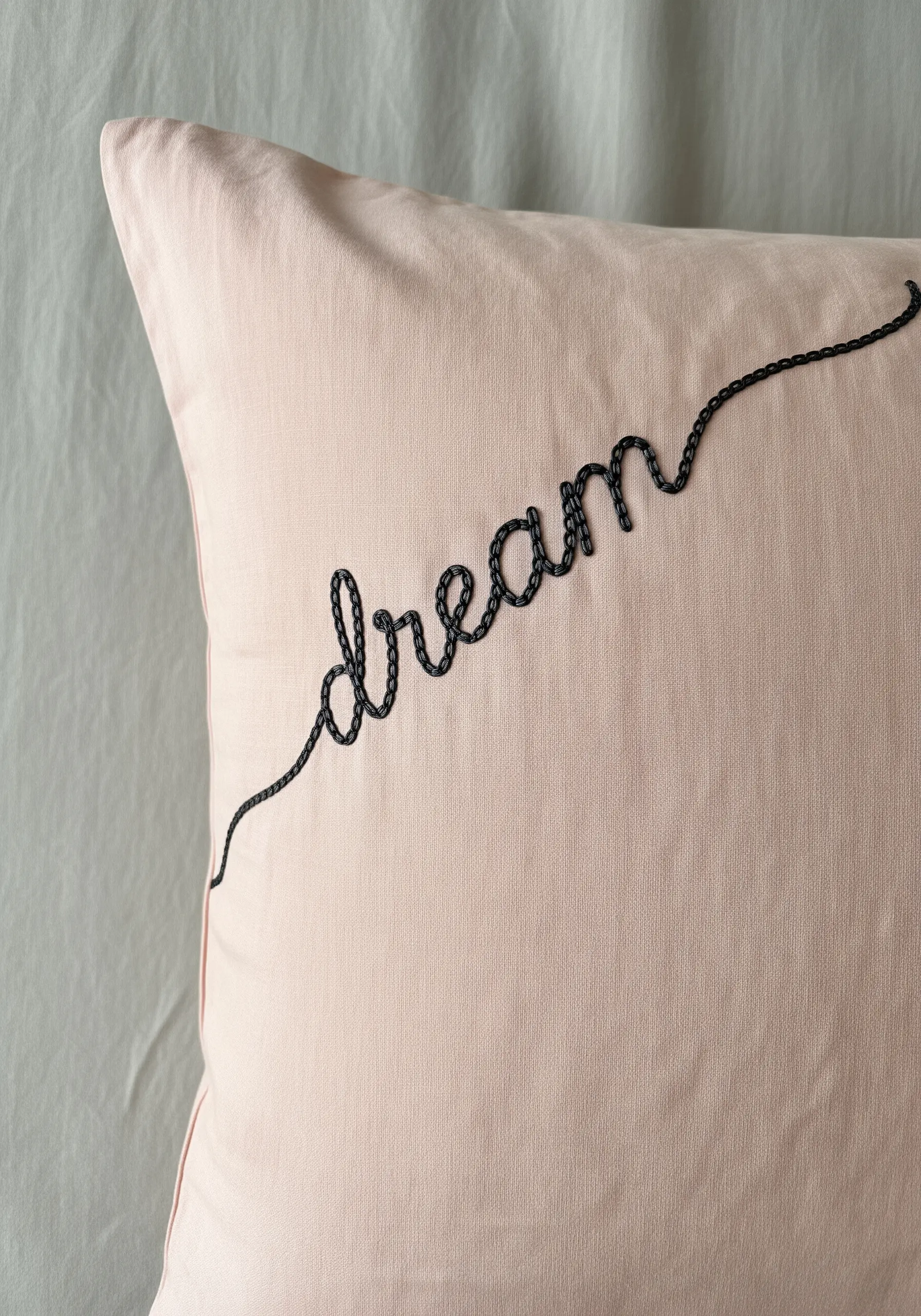 The word 'dream' embroidered in a flowing cursive script using a thick black chain stitch.