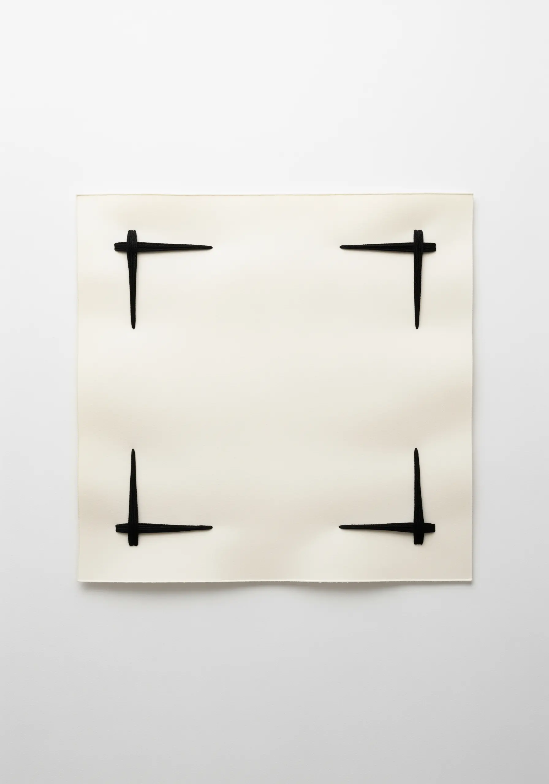 Four bold, black satin-stitched corner marks on a plain, off-white background.