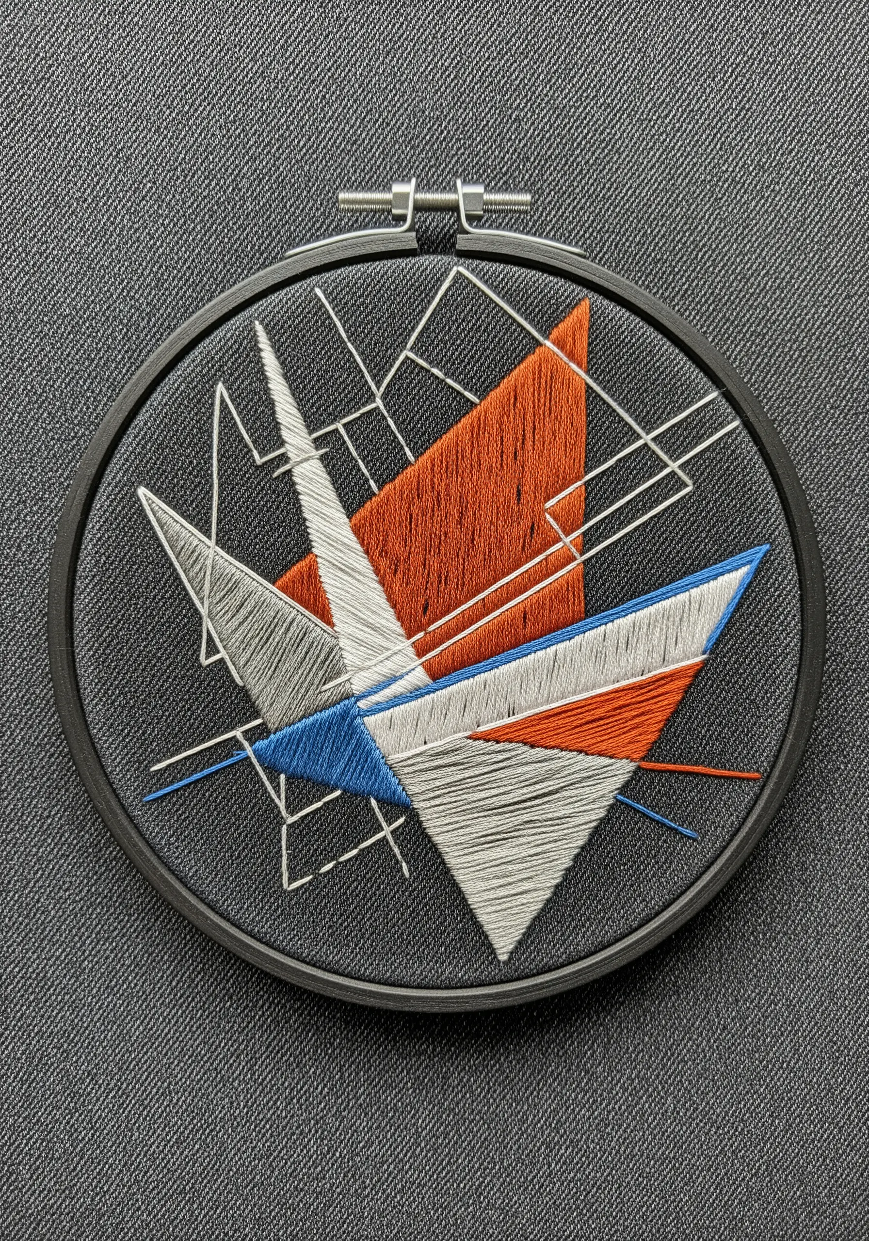 Abstract geometric embroidery with satin stitch triangles overlaid with thin white lines.