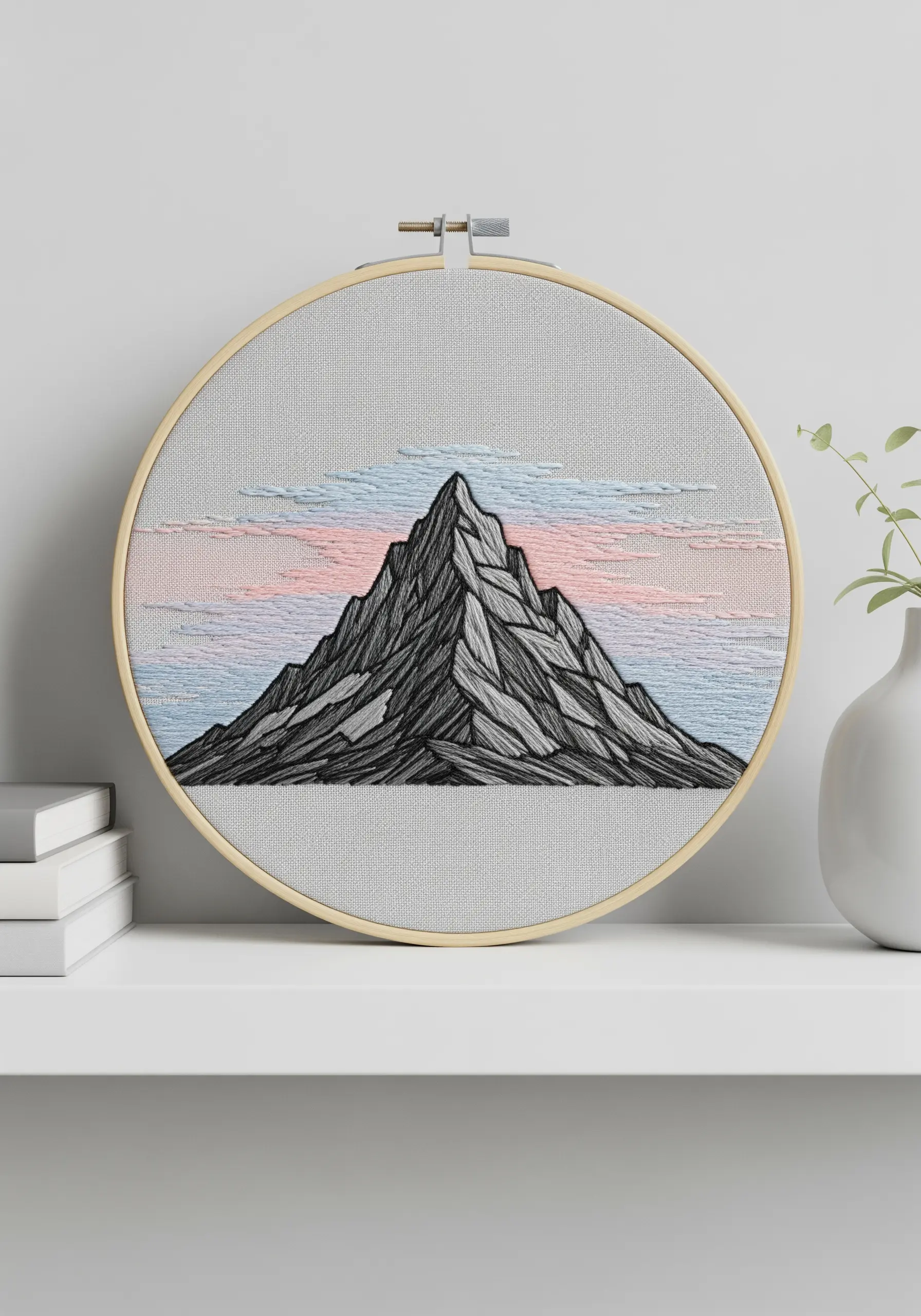 Minimalist line-art embroidery of a mountain peak with a soft pastel sky.