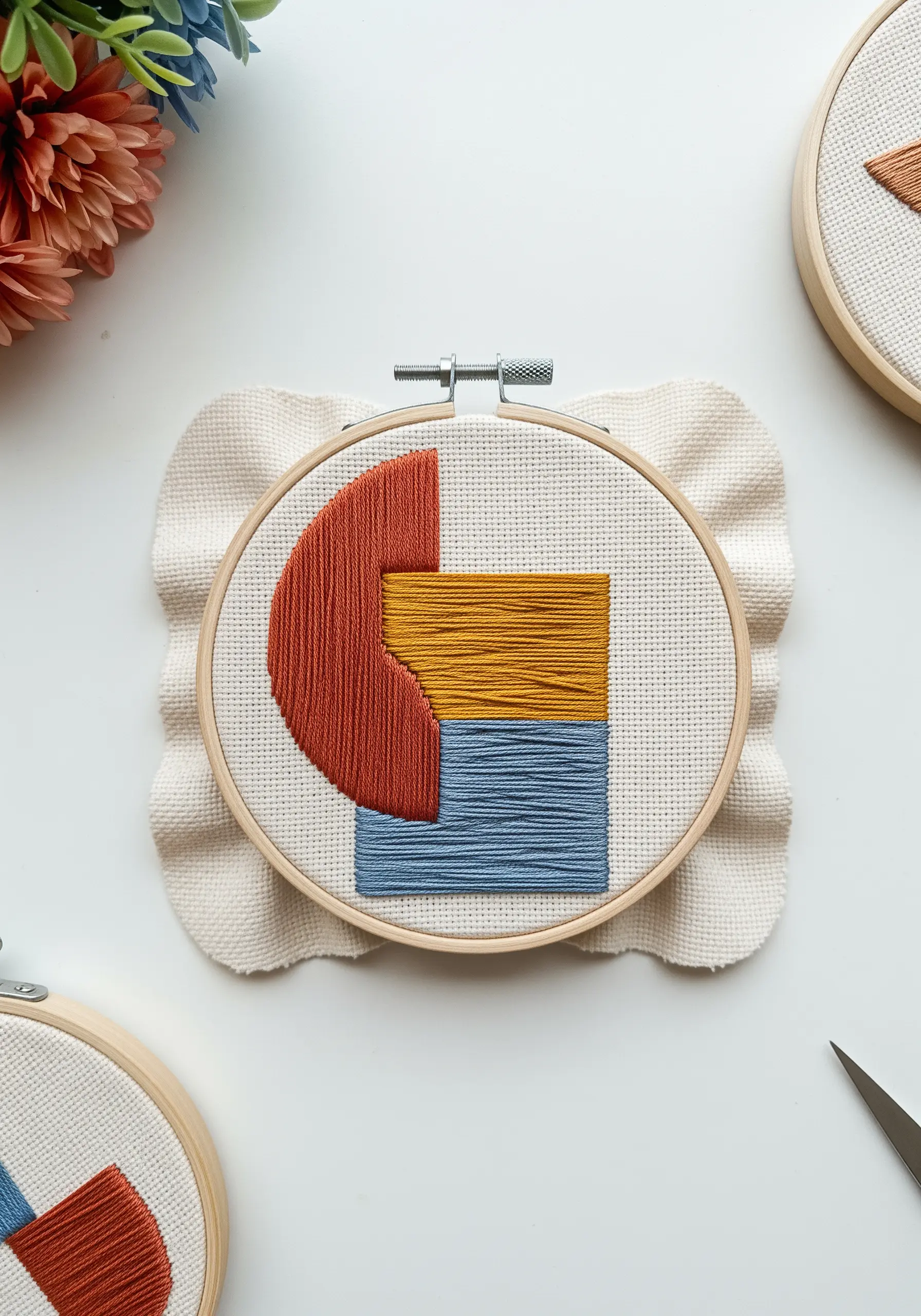 Abstract geometric shapes in red, yellow, and blue filled with satin stitch.